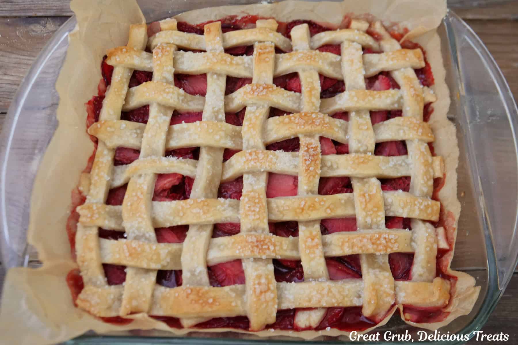 A glass baking dish with a baked strawberry pie bars that just came out of the oven.