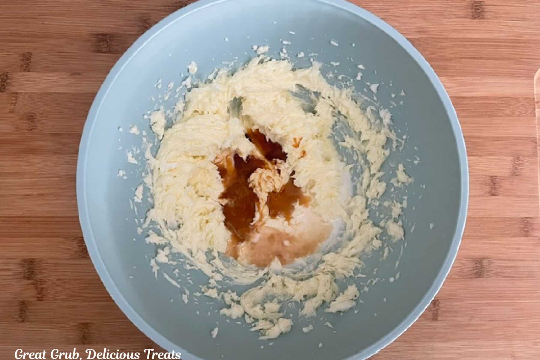 A light blue bowl with wet sugar cookie ingredients in it.