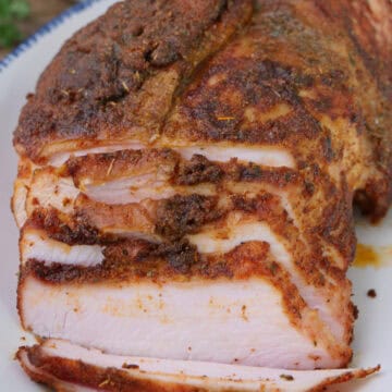 A blue trimmed white plate with a smoked Cajun turkey breast on it with a few slices cut, and a title overlay at the top.