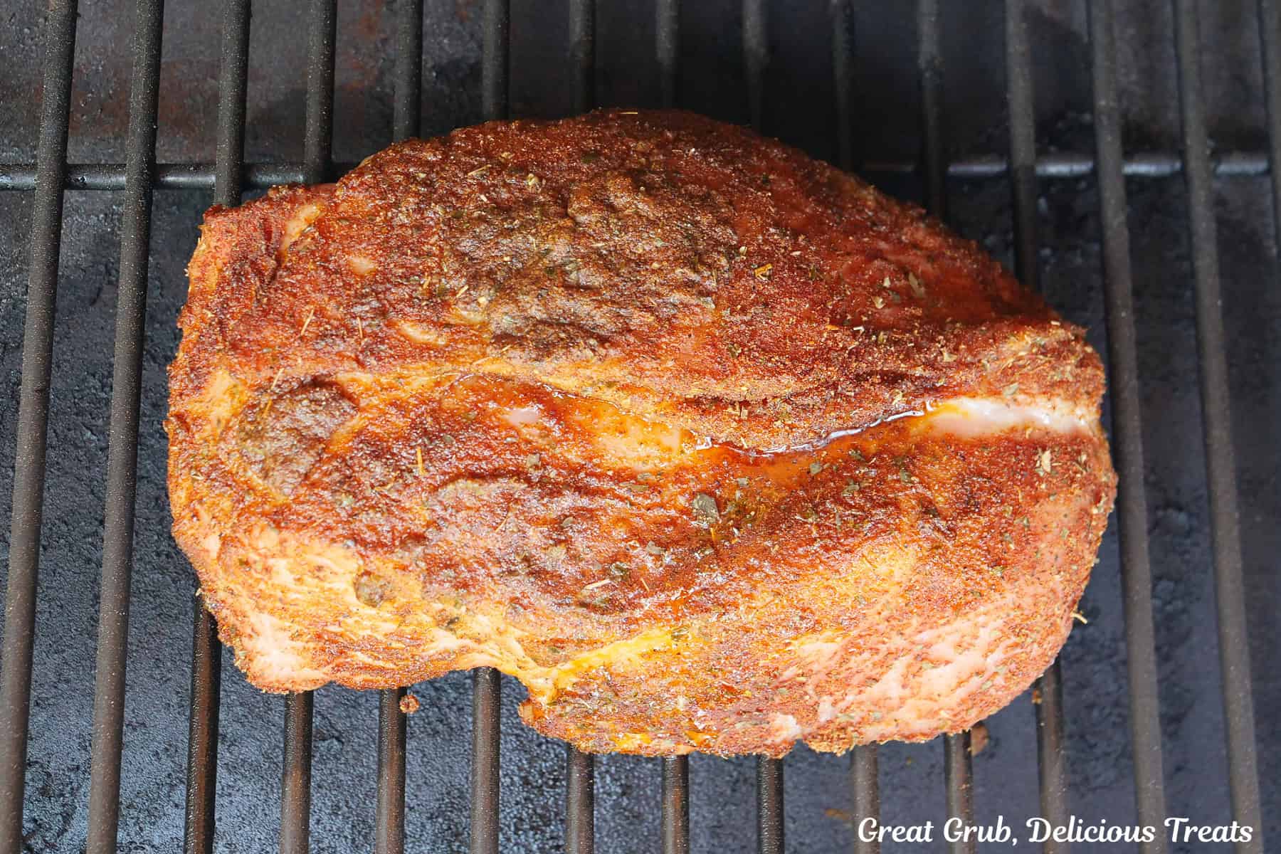 A turkey breast roast smoking directly on the grill grates of a smoker.