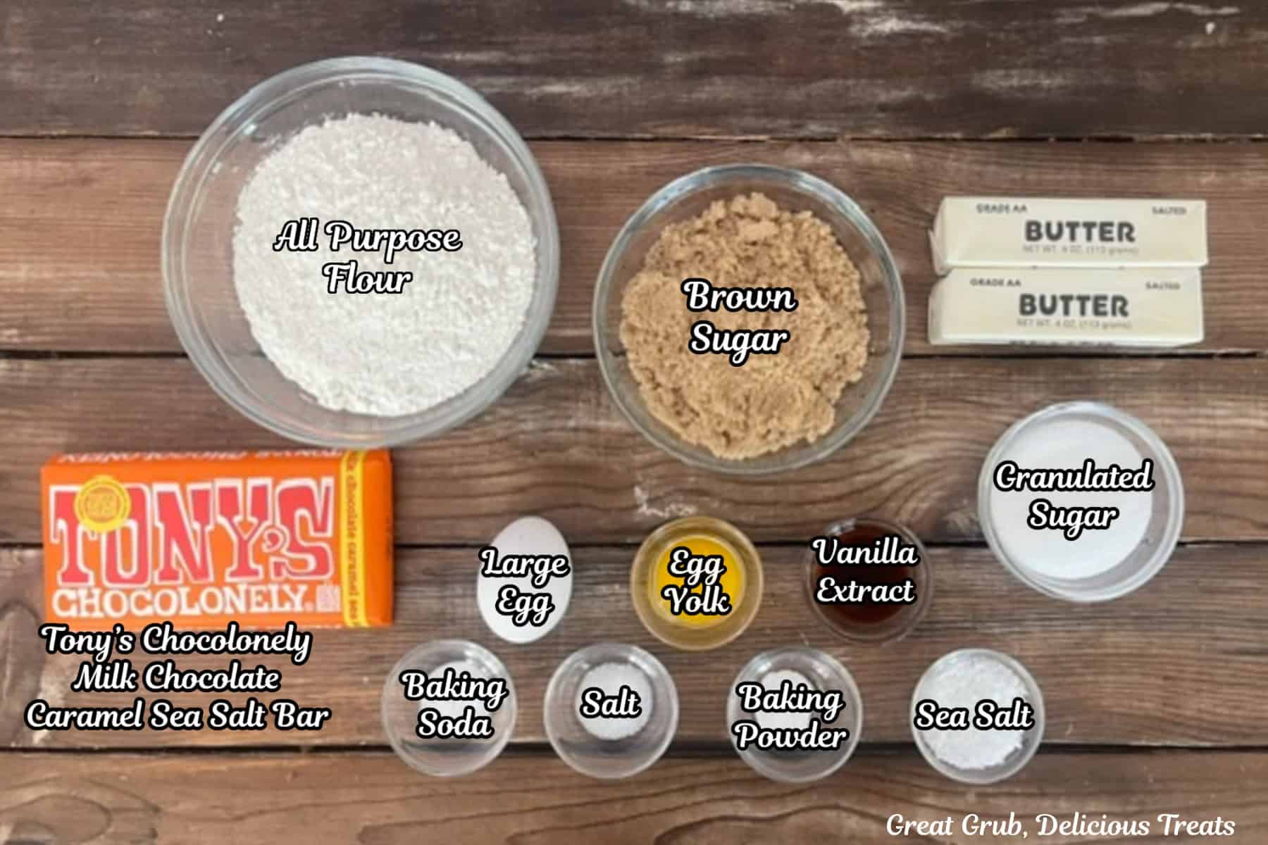 A wood surface with all the ingredients placed on it to make chocolate caramel cookies.
