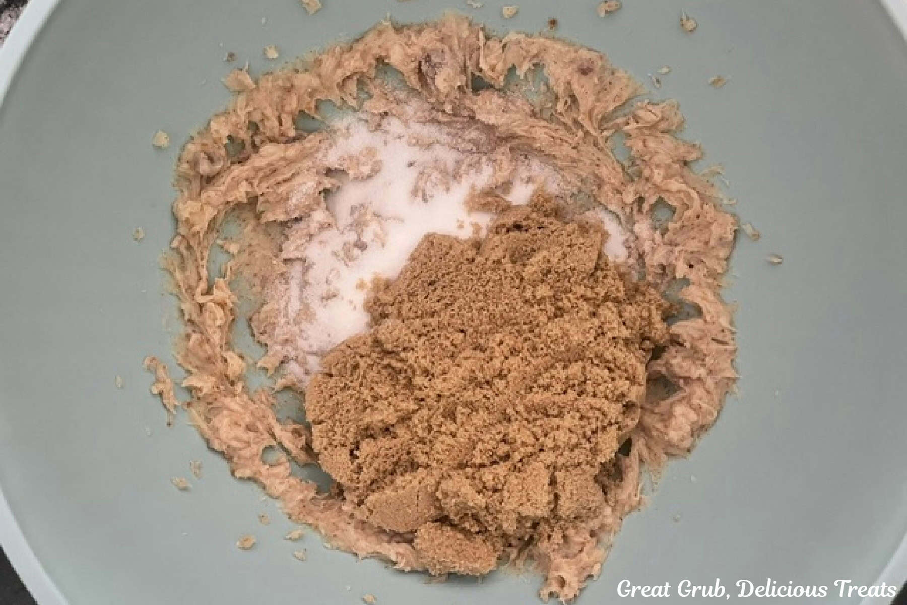 A mixing bowl with browned butter, brown sugar, and sugar in it before being combined.
