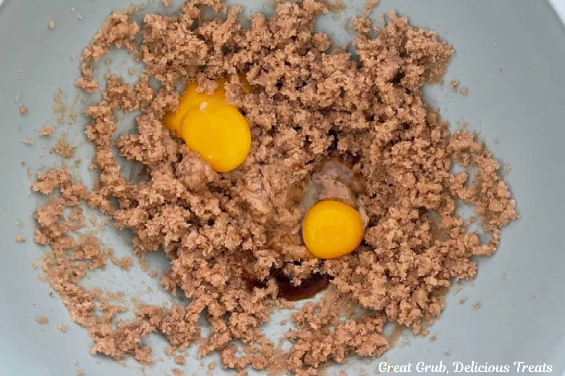 Brown butter cookie batter with eggs and vanilla added to the bowl.