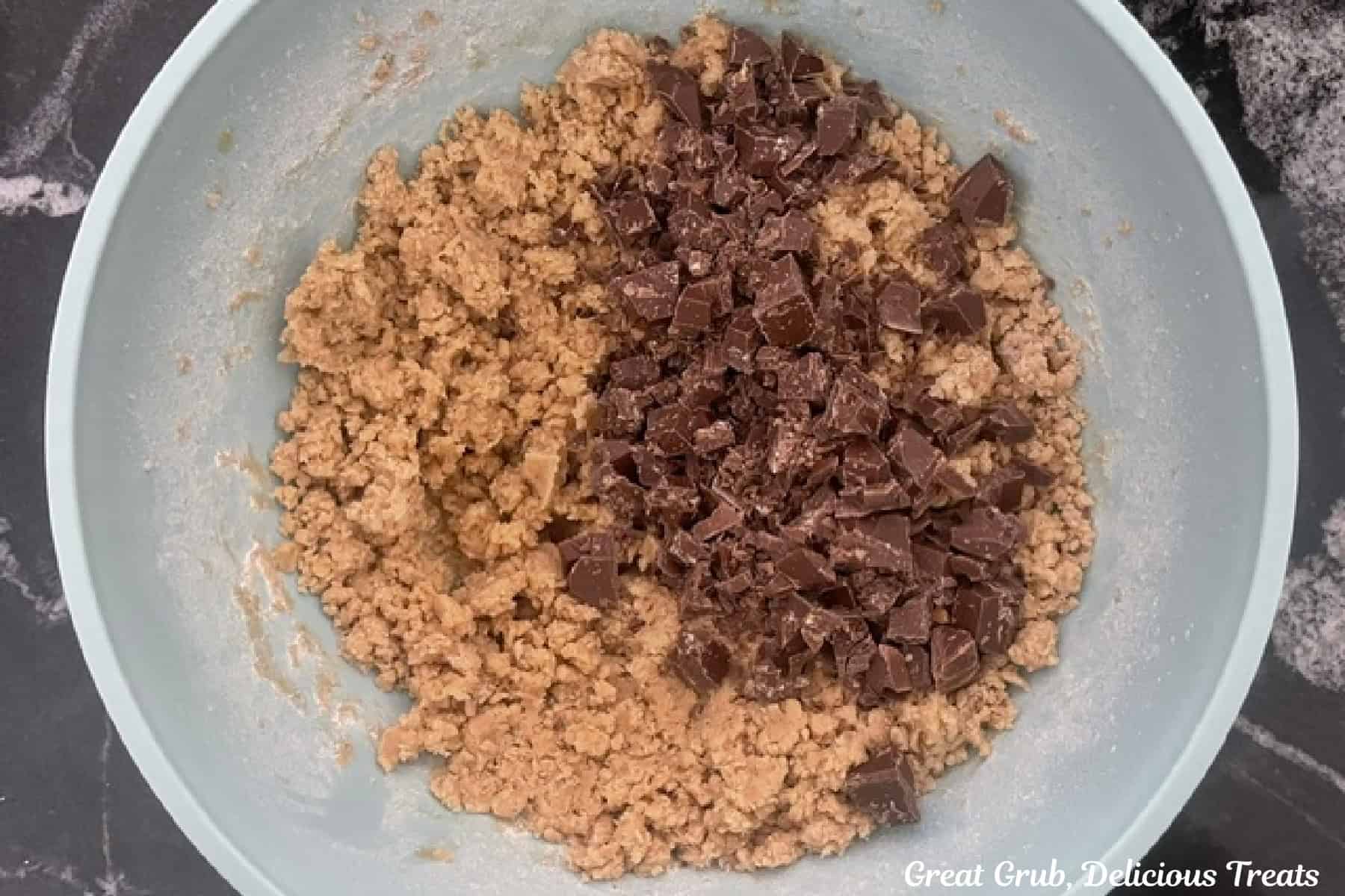A mixing bowl with brown butter cookie dough batter with chocolate caramel chunks added to the dough.