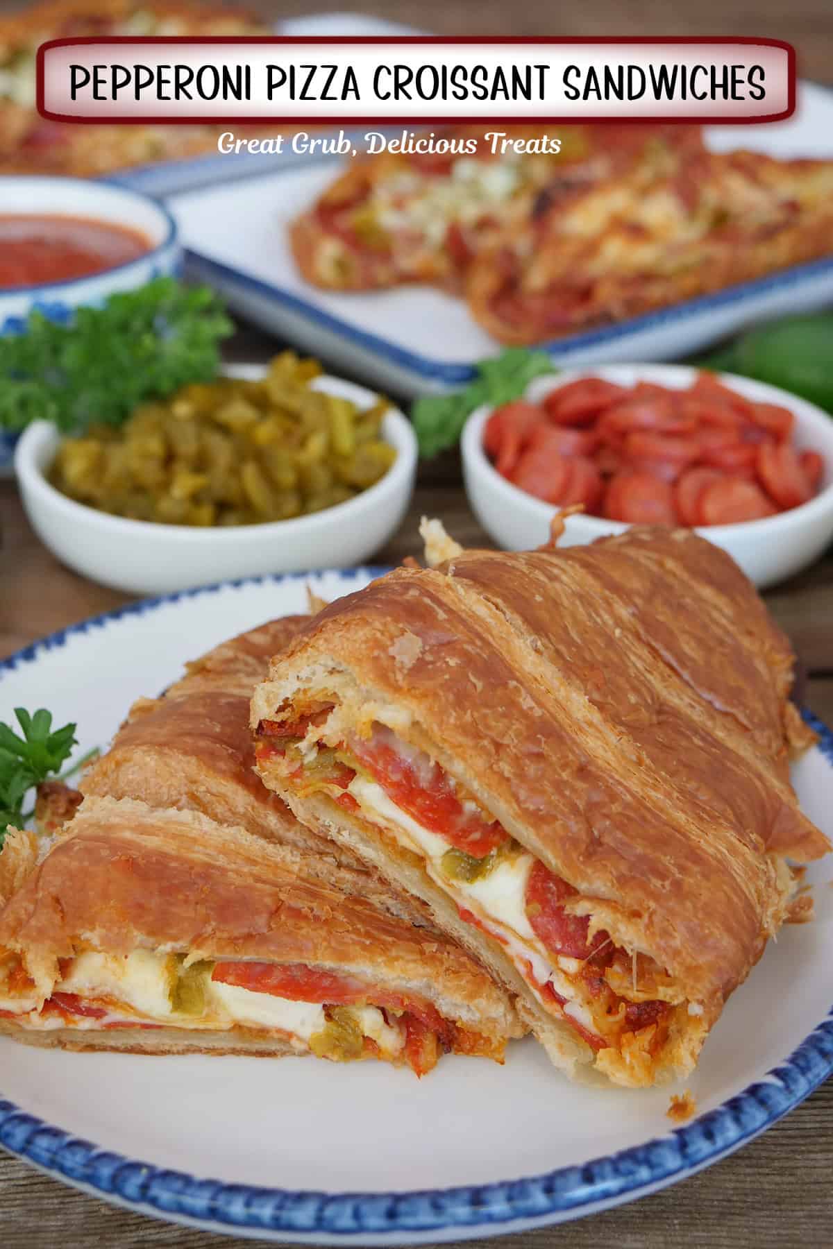 A white plate with blue trim with a pepperoni pizza croissant sandwich that is cut in half placed on it, with a title overlay at the top.