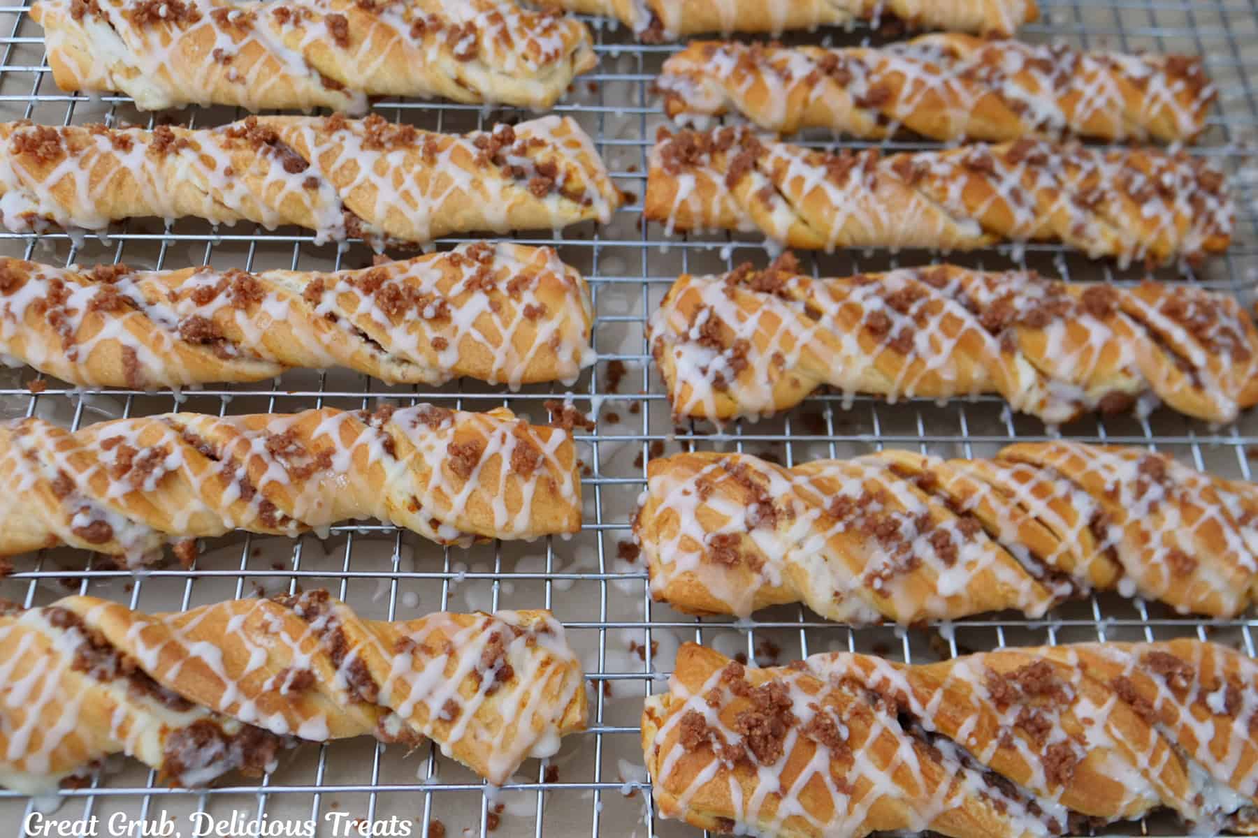 A wire rack with eleven pumpkin cream cheese streusel twists on it.