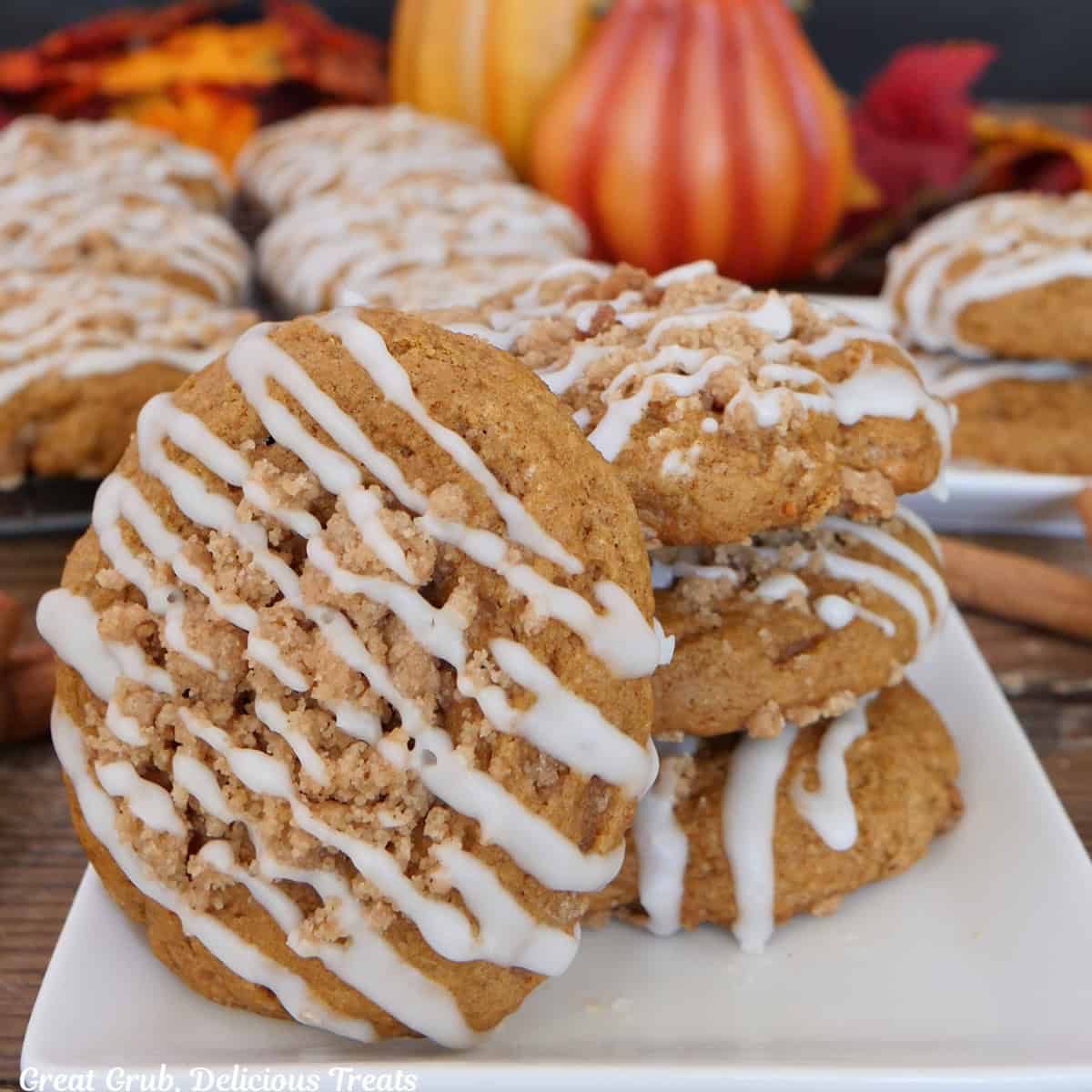 A white plate with four pumpkin streusel cookies on it with more cookies in the background.