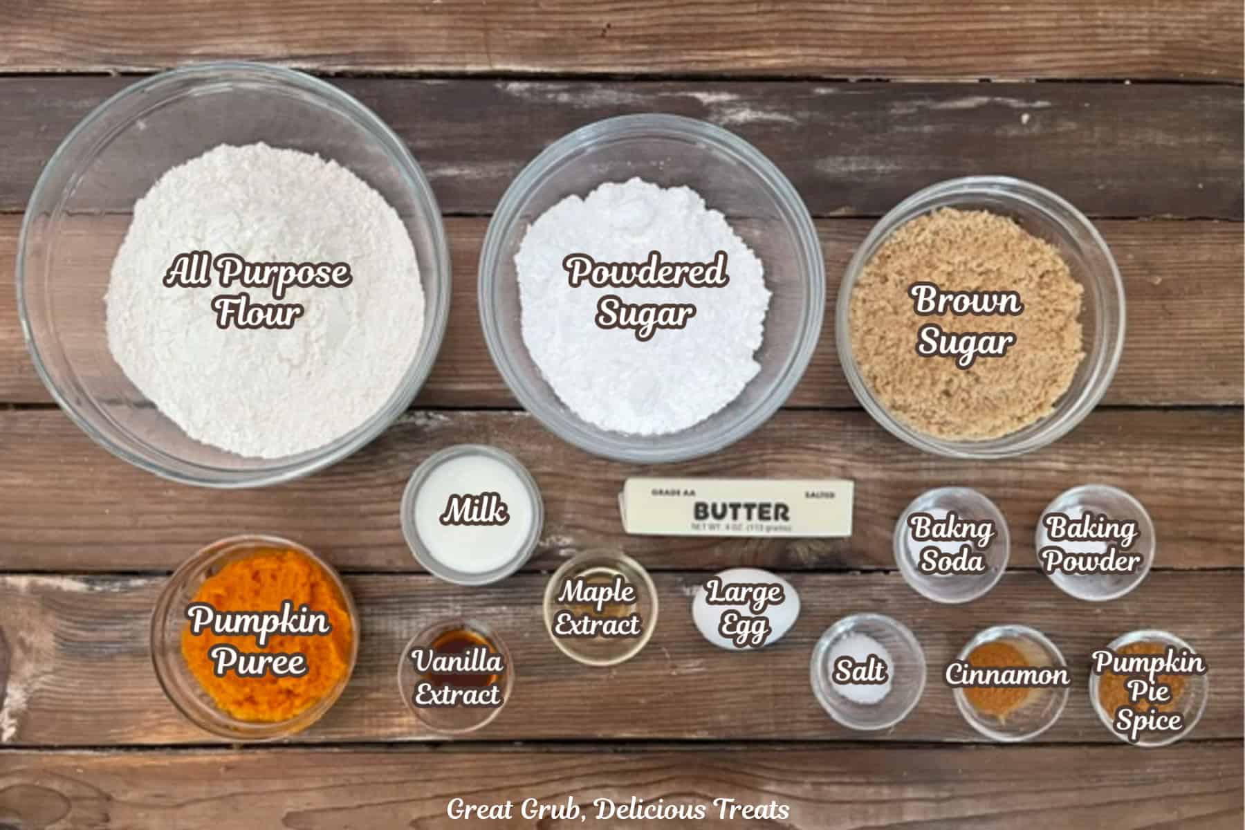 A rustic wood surface with all the ingredients placed on it to make pumpkin streusel cookies with maple icing.