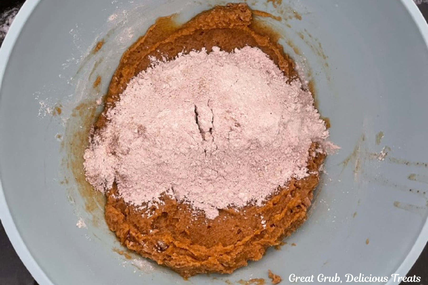 A light colored bowl with the wet pumpkin ingredients and the dry flour ingredients added and not yet combined.