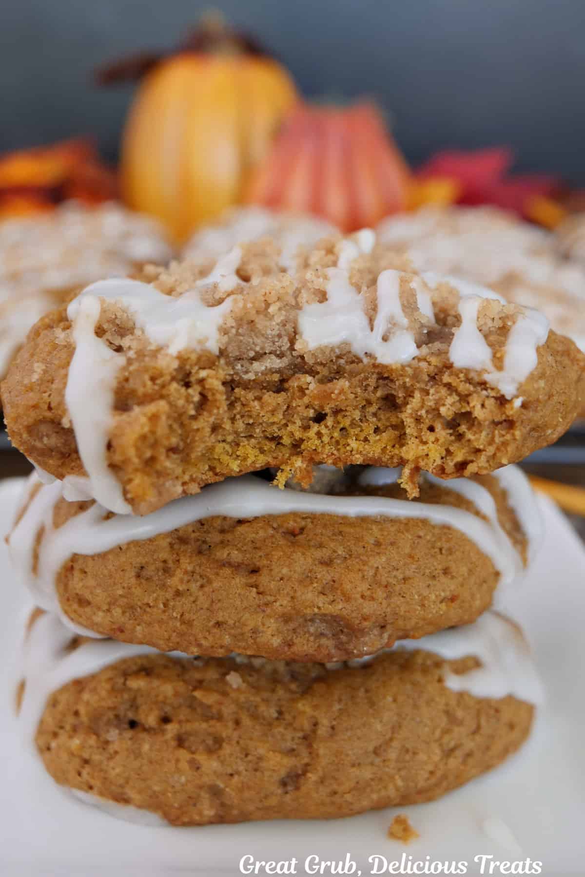 a white plate with three pumpkin cookies on it with a bite taken out of the top cookies.