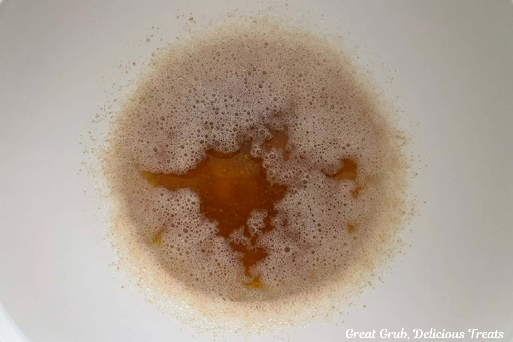 A white mixing bowl with cooked brown butter in it cooling.