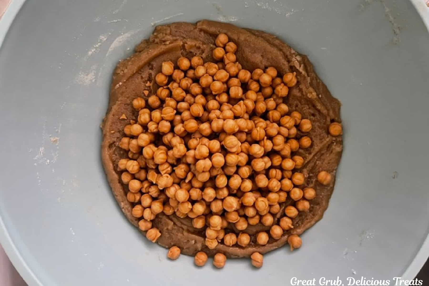 A white mixing bowl with blondie batter and caramel bits added.
