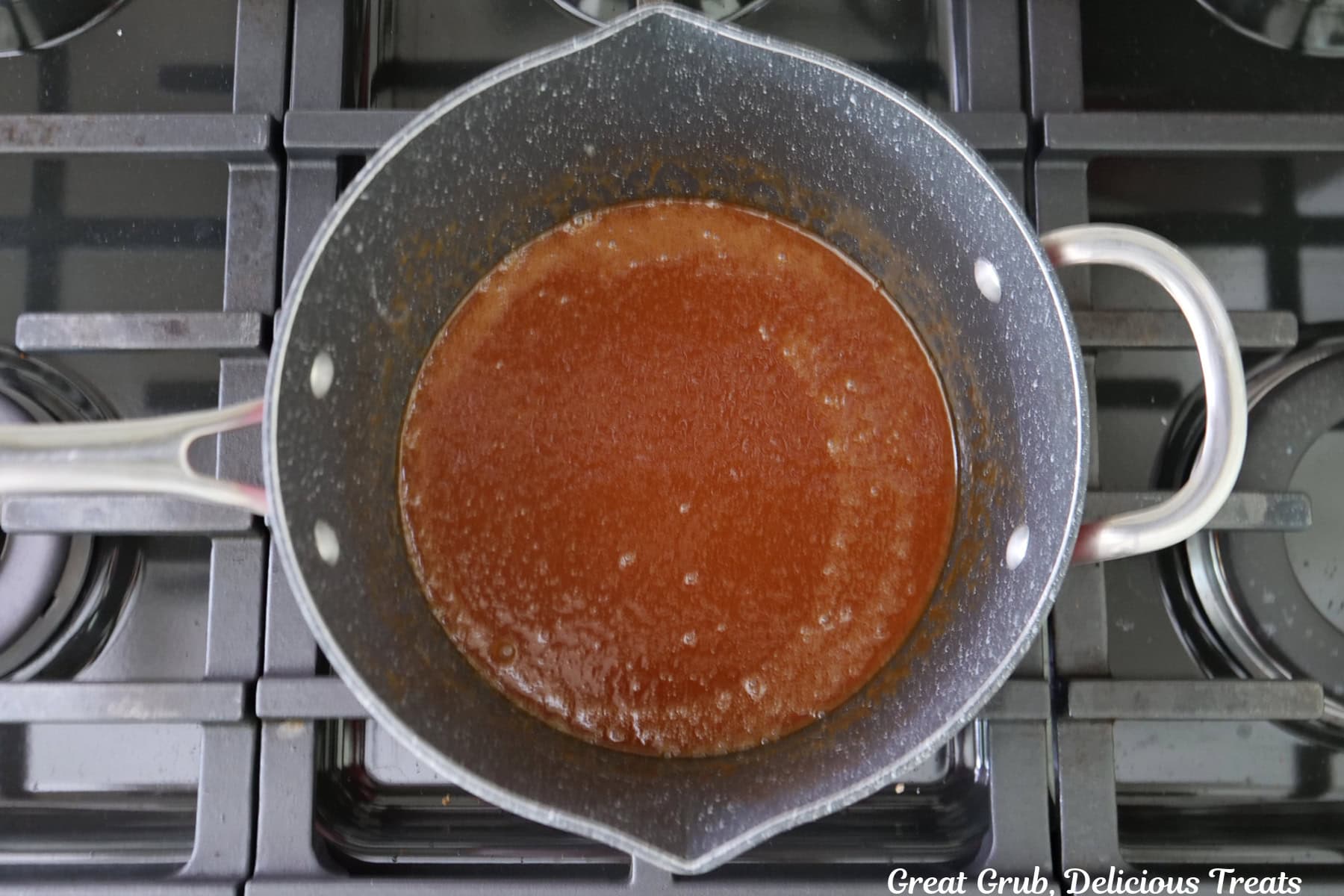 A saucepan with homemade caramel sauce in it.