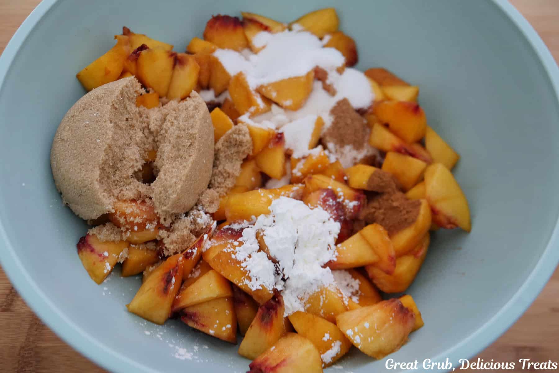 A light blue mixing bowl with the fresh peach filling ingredients in it before being mixed together.
