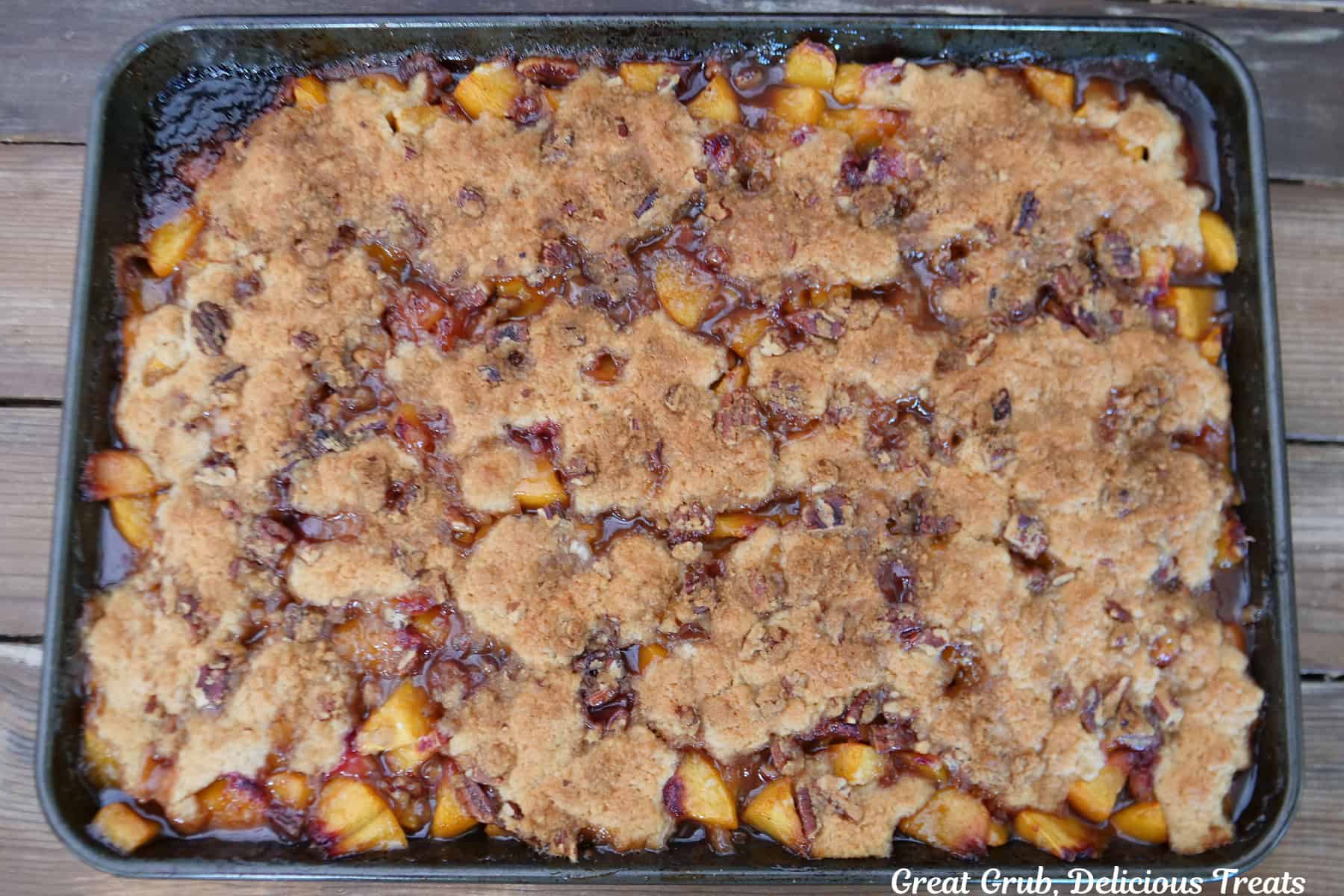 A baking sheet with a baked sheet pan peach cobbler on it after being removed from the oven.