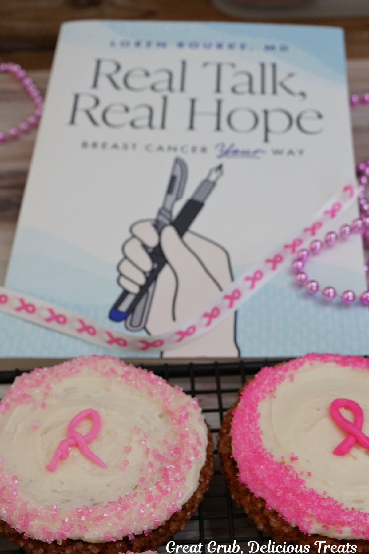 Two frosted molasses cookies with Dr. Loren Rourke's new book, Real Talk, Real Hope in the background.