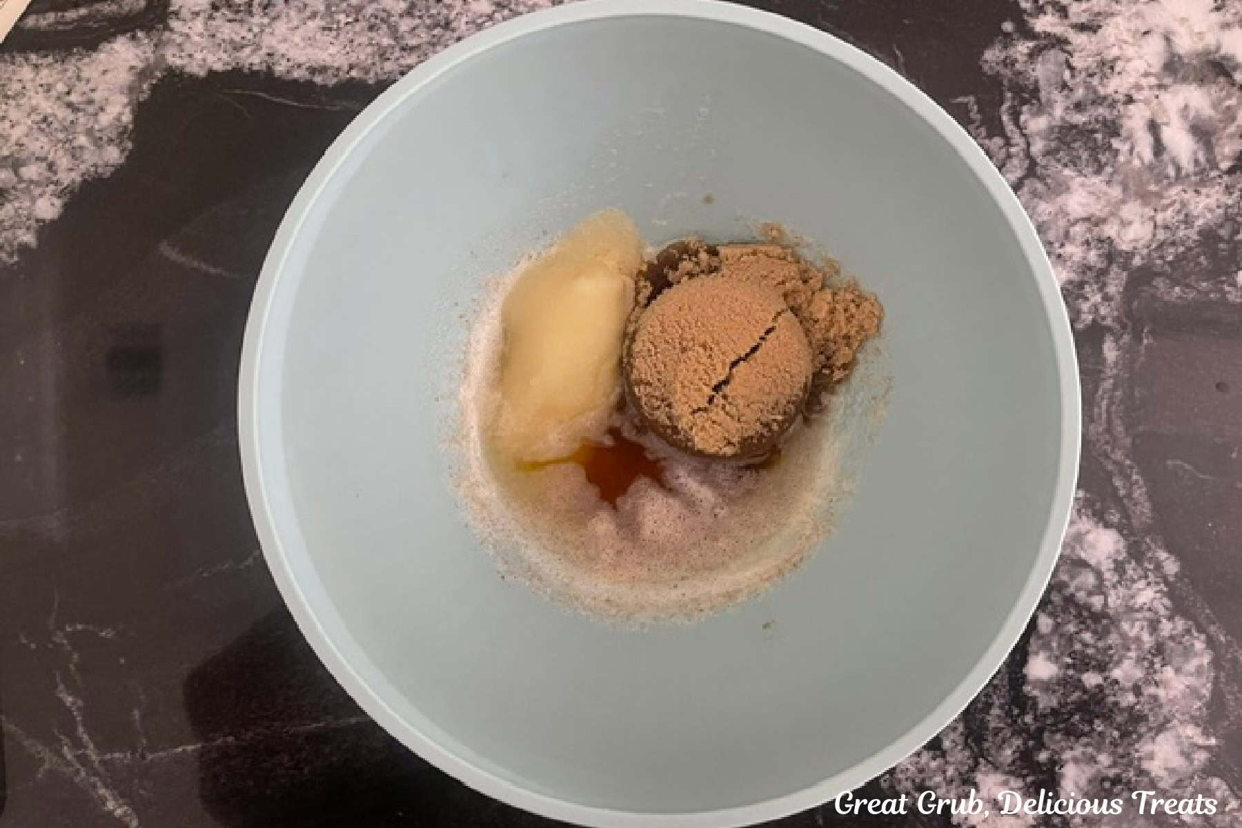 A mixing bowl with browned butter, brown sugar and granulated sugar in it.