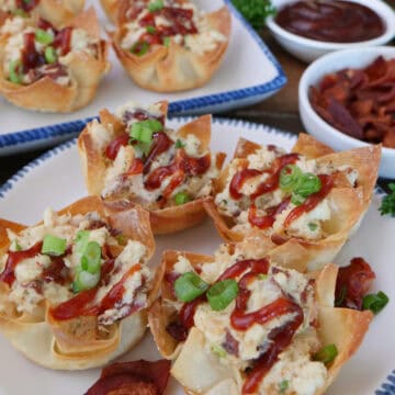 A white plate with blue trim with four chicken bacon ranch wonton cups on it with more in the background, and a title overlay at the top.