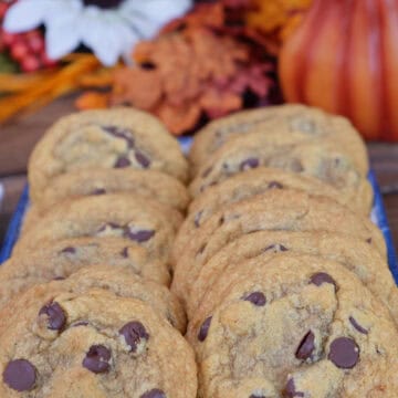 A dozen chocolate chip pumpkin cookies on a plate with fall foliage in the background, and a title overlay at the top.
