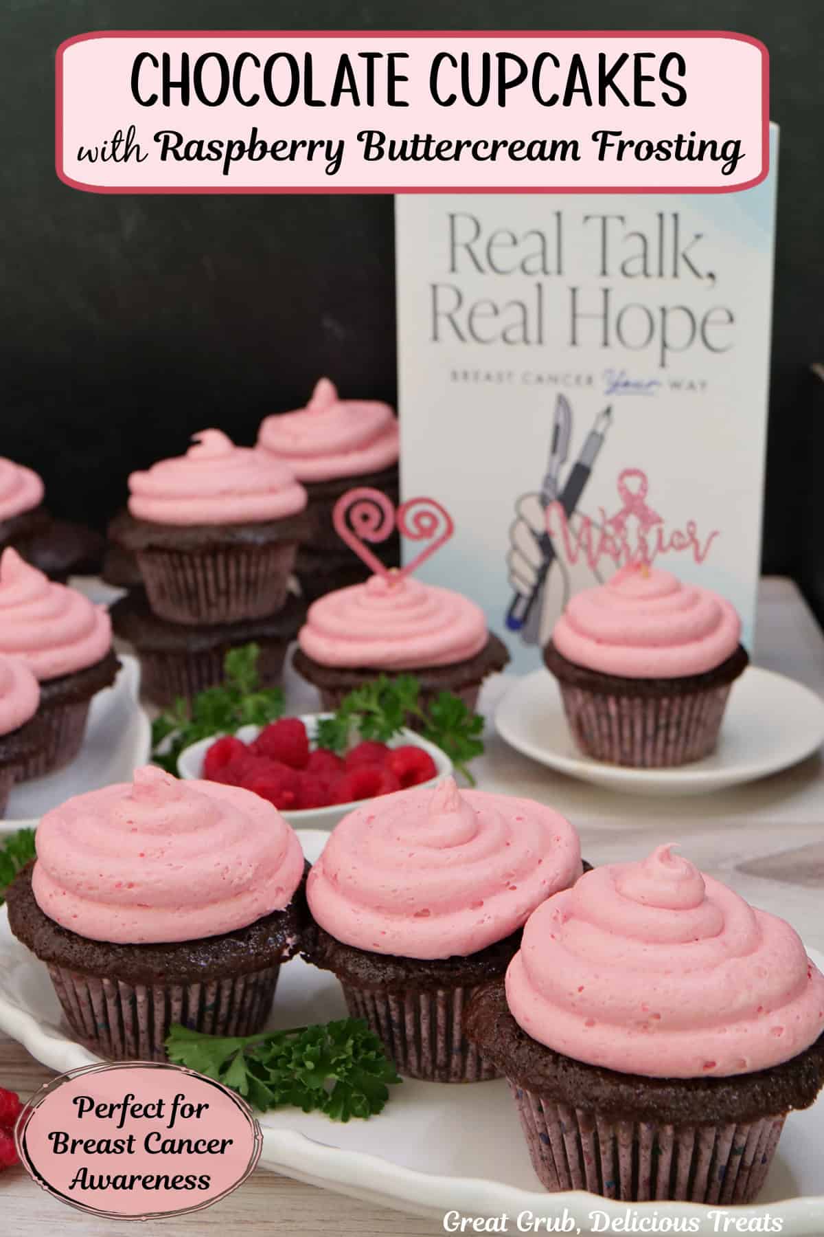 A wood surface with five small white plates with chocolate cupcakes with raspberry buttercream frosting on top, with Dr. Loren Rourke's Real Talk, Real Hope off to the side, and fresh raspberries randomly placed about.