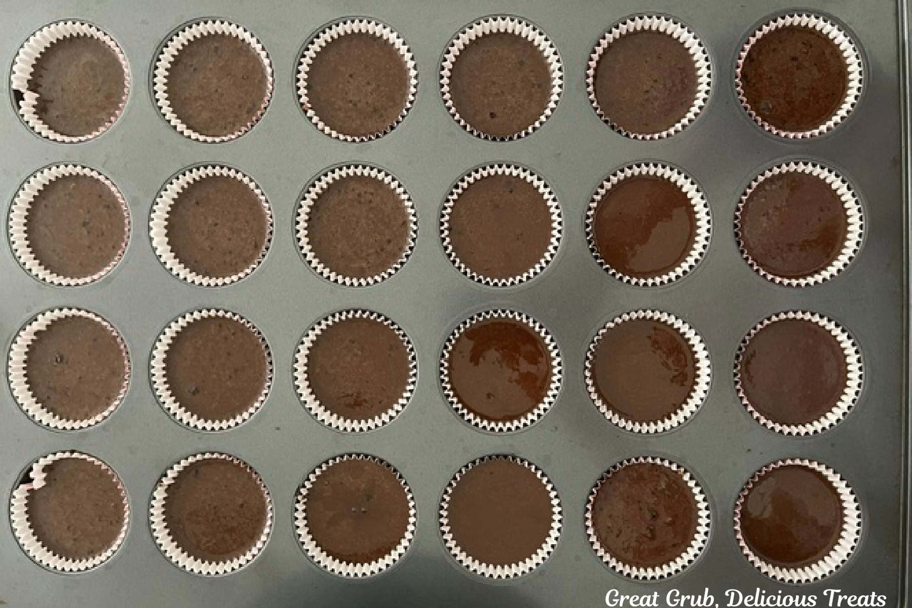 A 24-count muffin tin with chocolate cupcake batter in the cupcake liners before being baked.