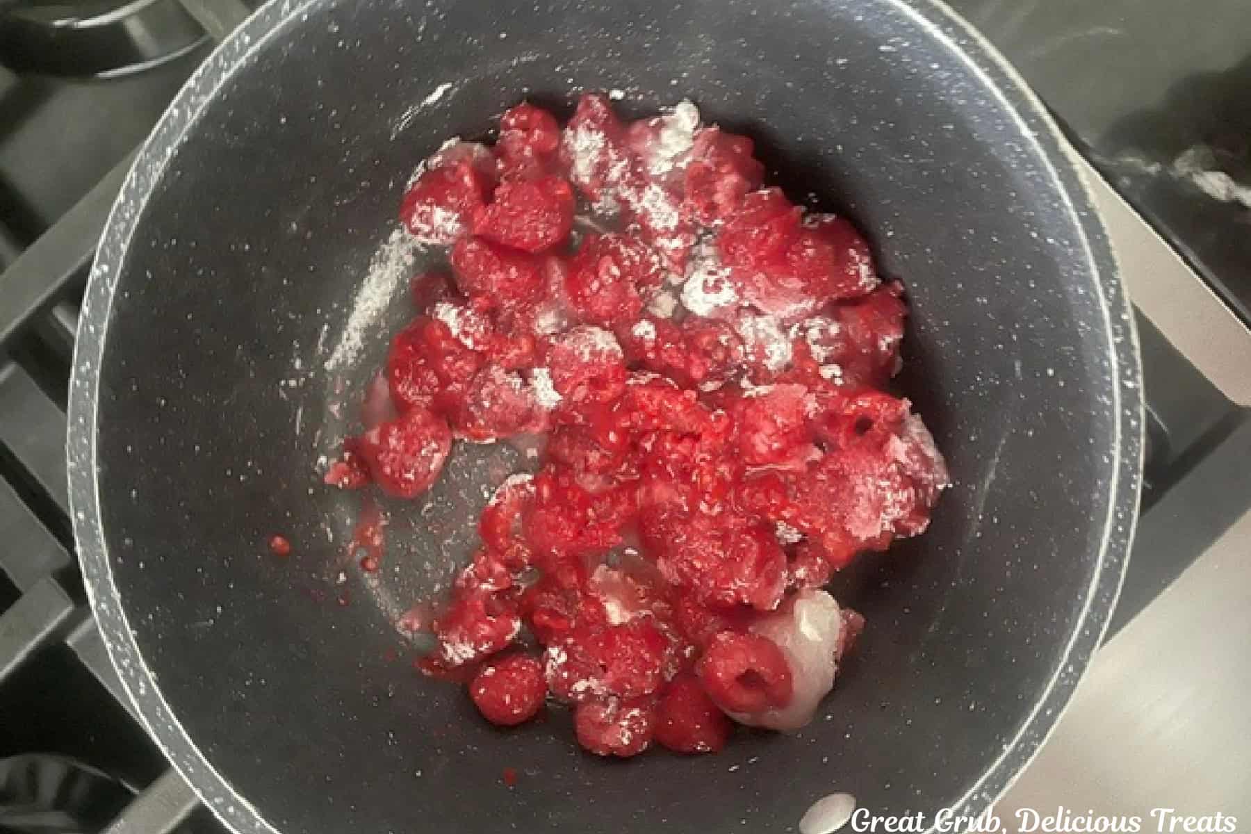 A saucepan with fresh raspberries, sugar, lemon juice, and cornstarch in it before being cooked.