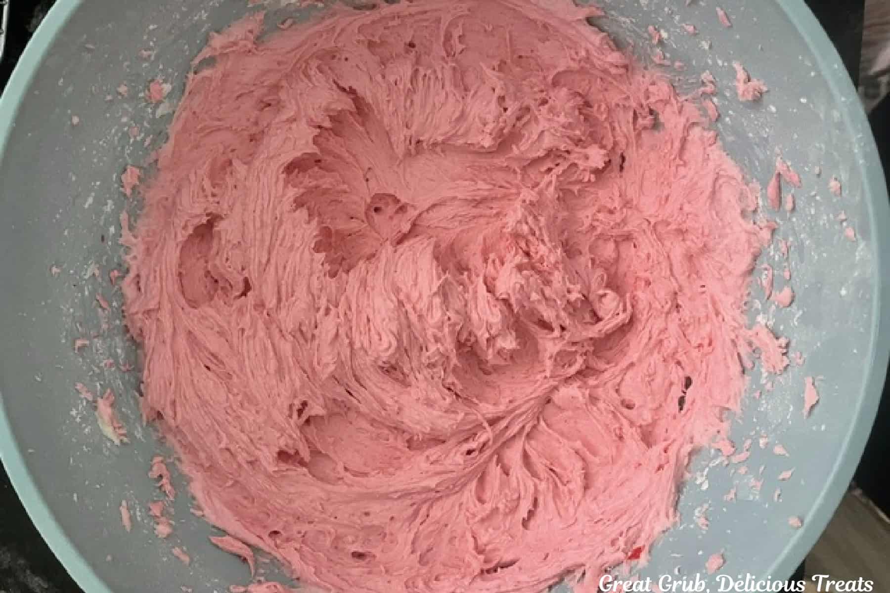 A mixing bowl with butter, raspberry sauce, and powdered sugar mixed together.