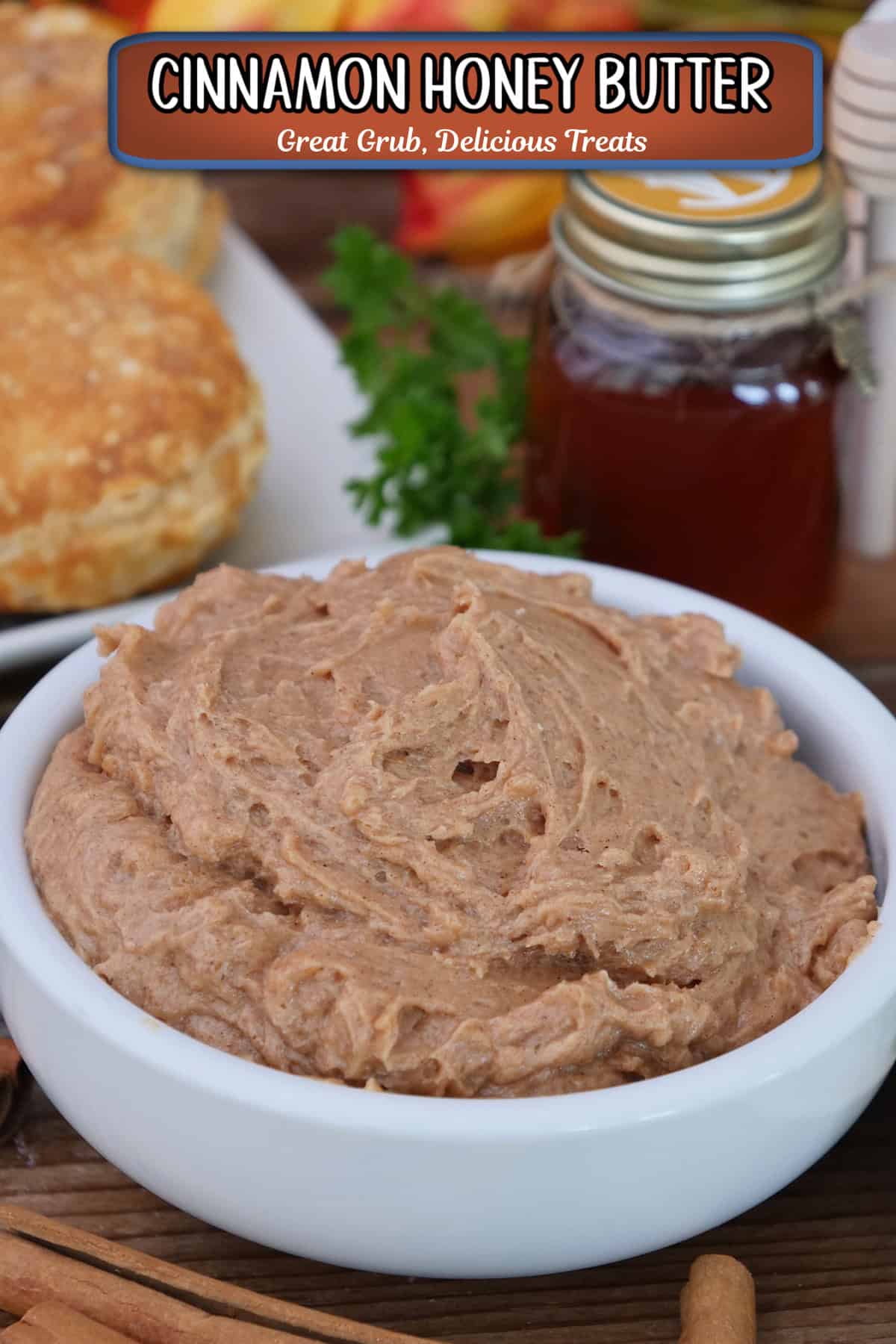 A white bowl filled with cinnamon honey butter, with a small bottle of honey and biscuits in the background, and a title overlay at the top.