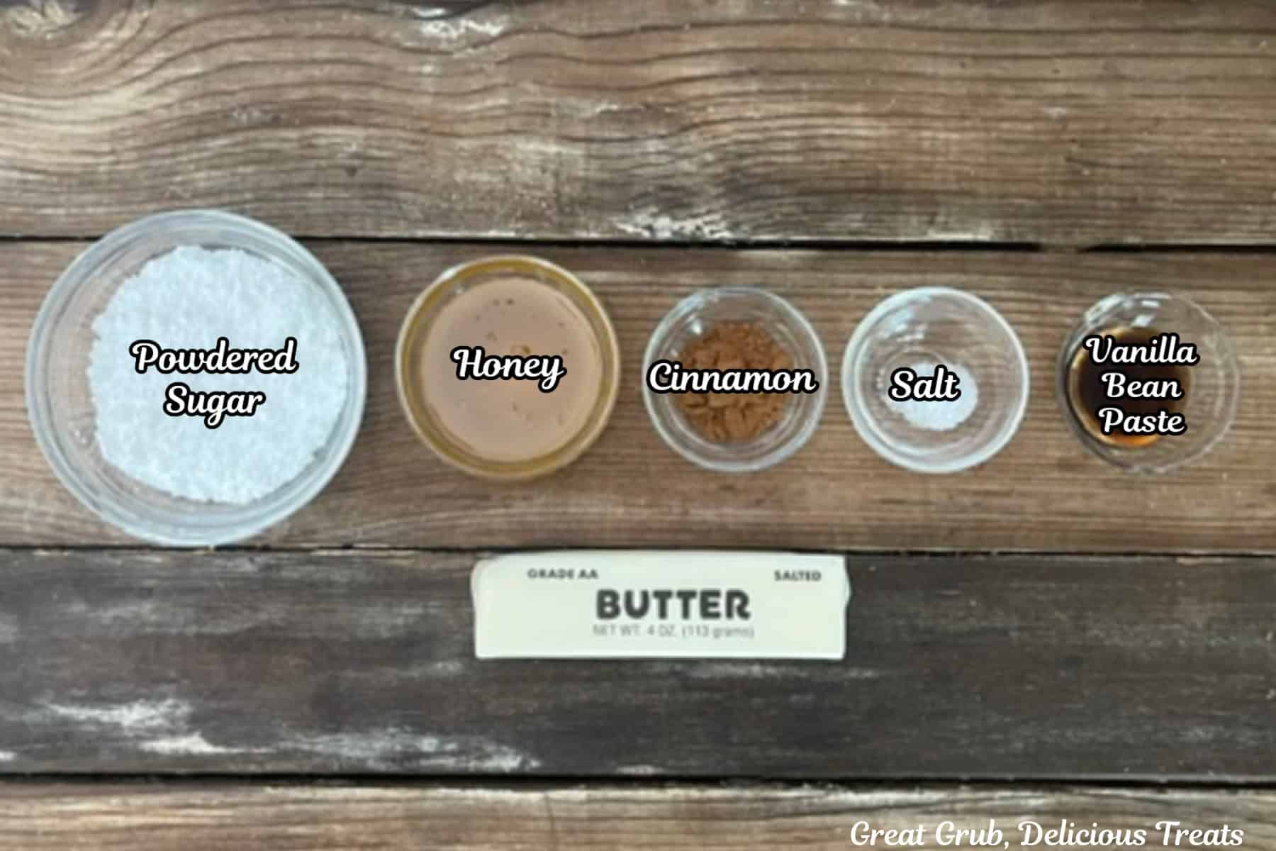 A rustic wood surface with all the ingredients placed on it to make cinnamon honey butter.