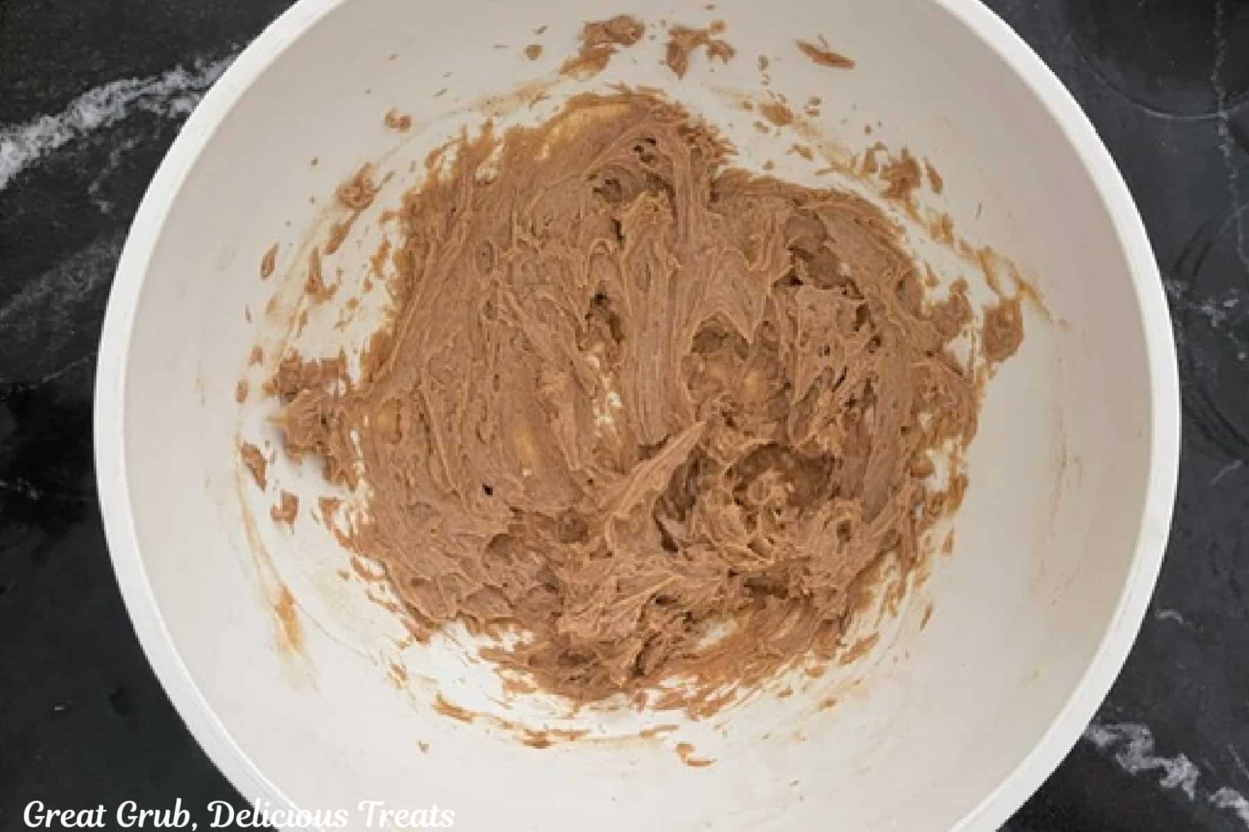 A white mixing bowl with cinnamon honey butter whipped together.