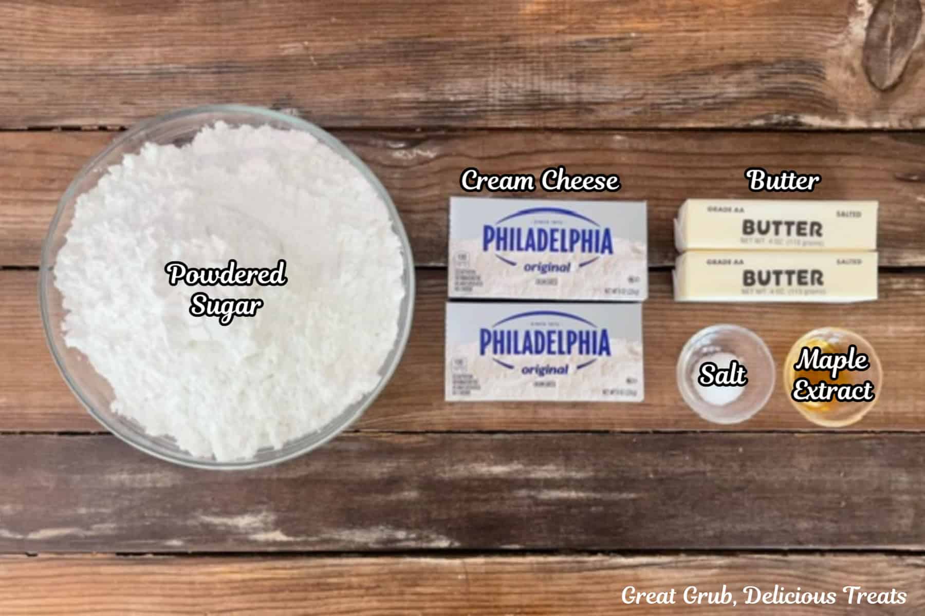 A wood surface with powdered sugar, cream cheese, butter, salt, and maple extract placed on it.