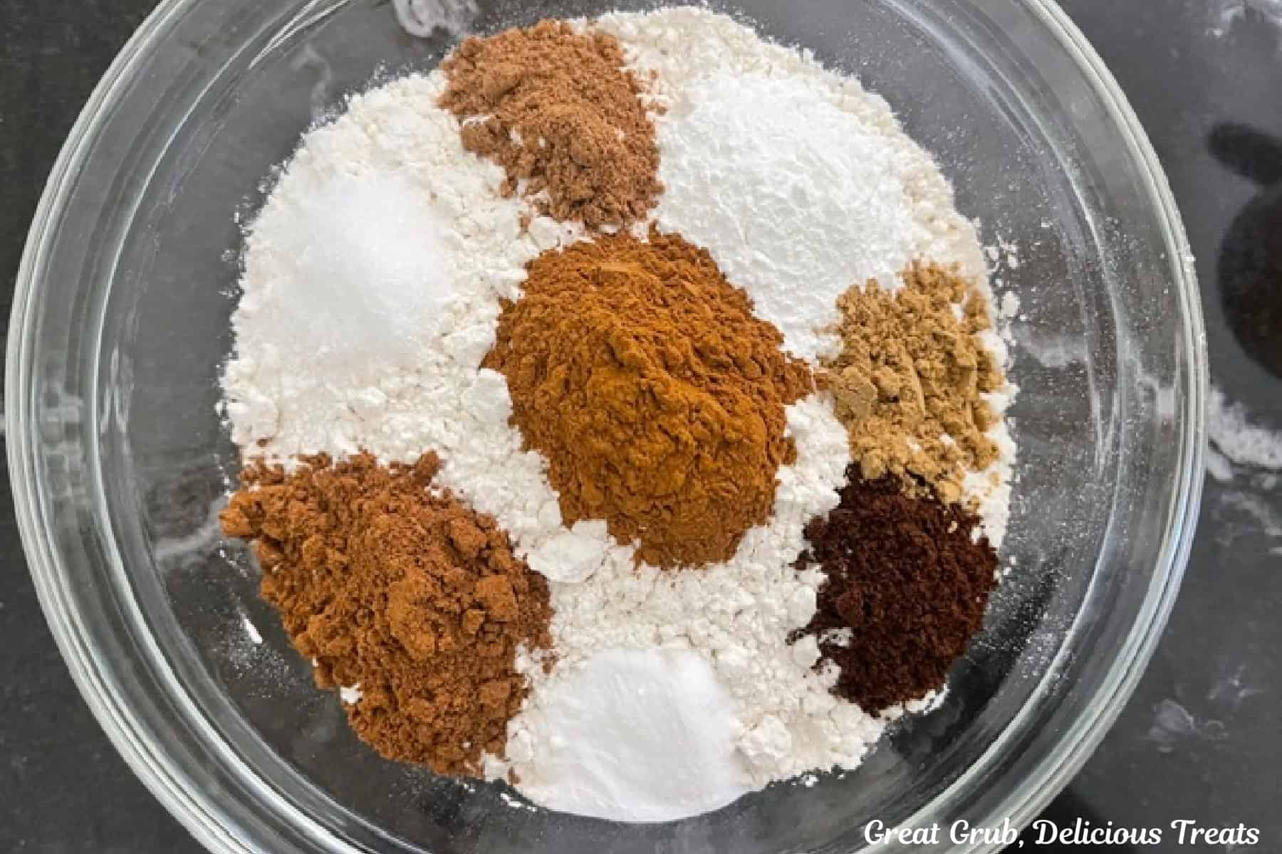 A glass bowl with flour and all the seasonings and dry ingredients in it for the pumpkin cupcakes.