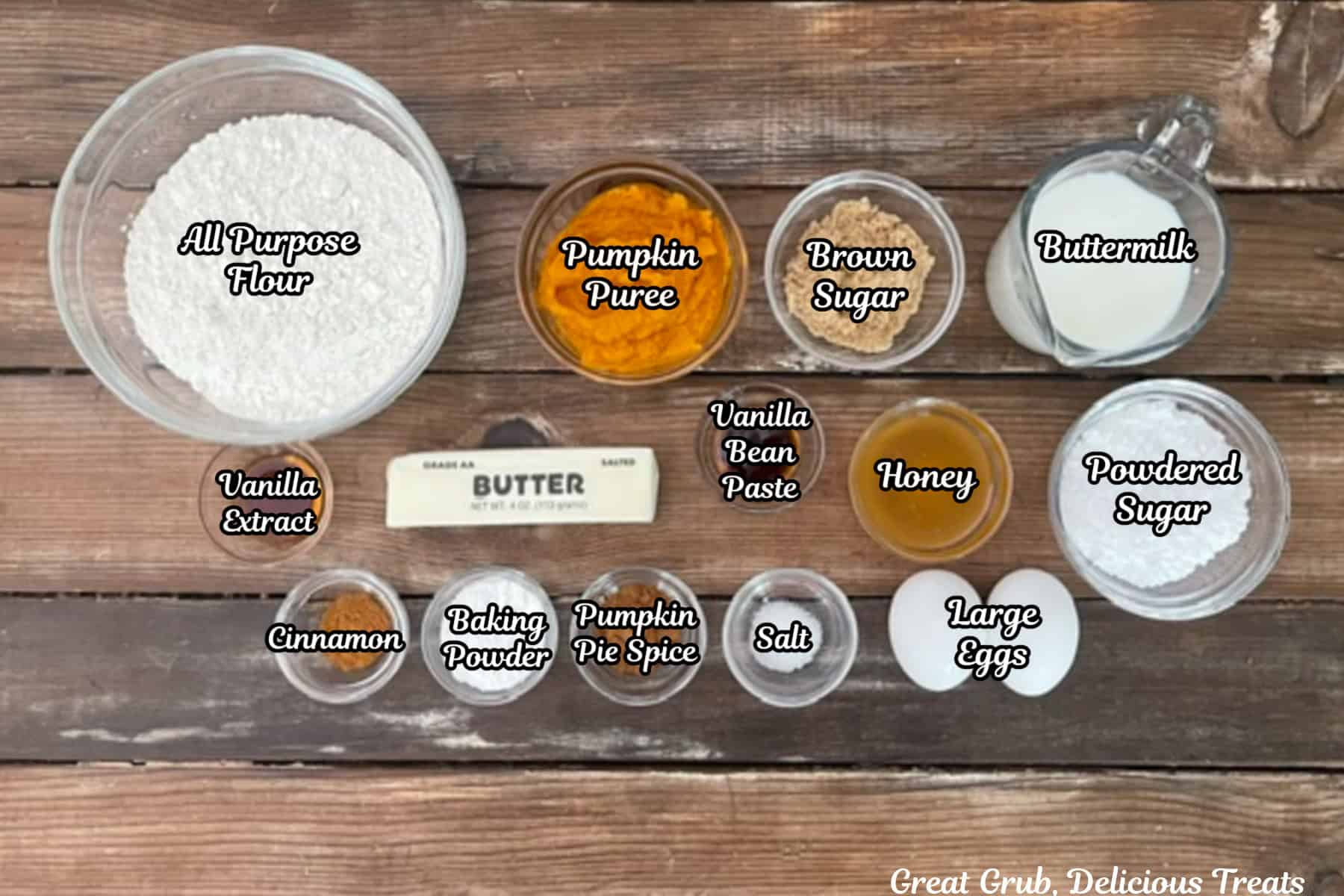 A wood surface with all the ingredients placed on it to make pumpkin spice waffles with cinnamon honey butter.