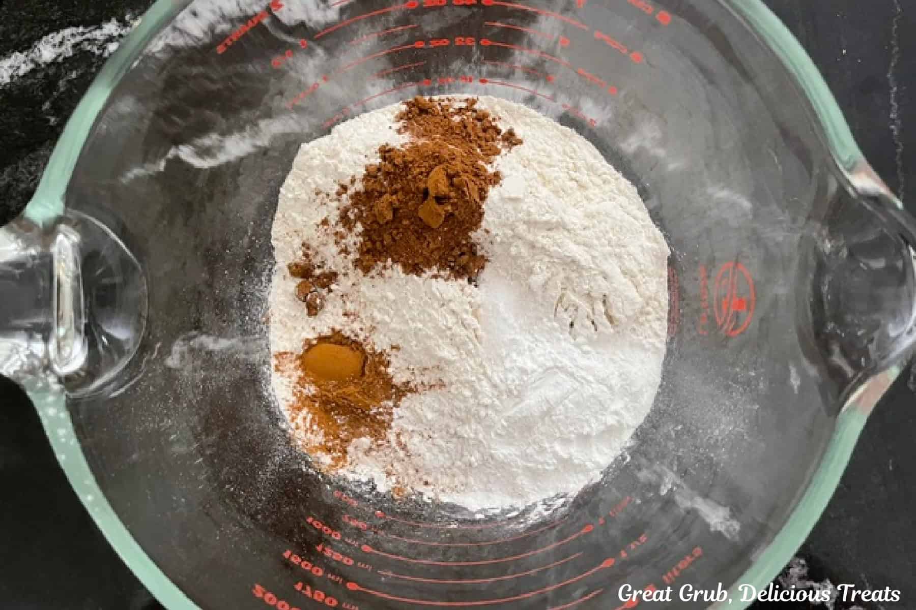 A large glass measuring cup with the dry waffle ingredients in it before being whisked together.