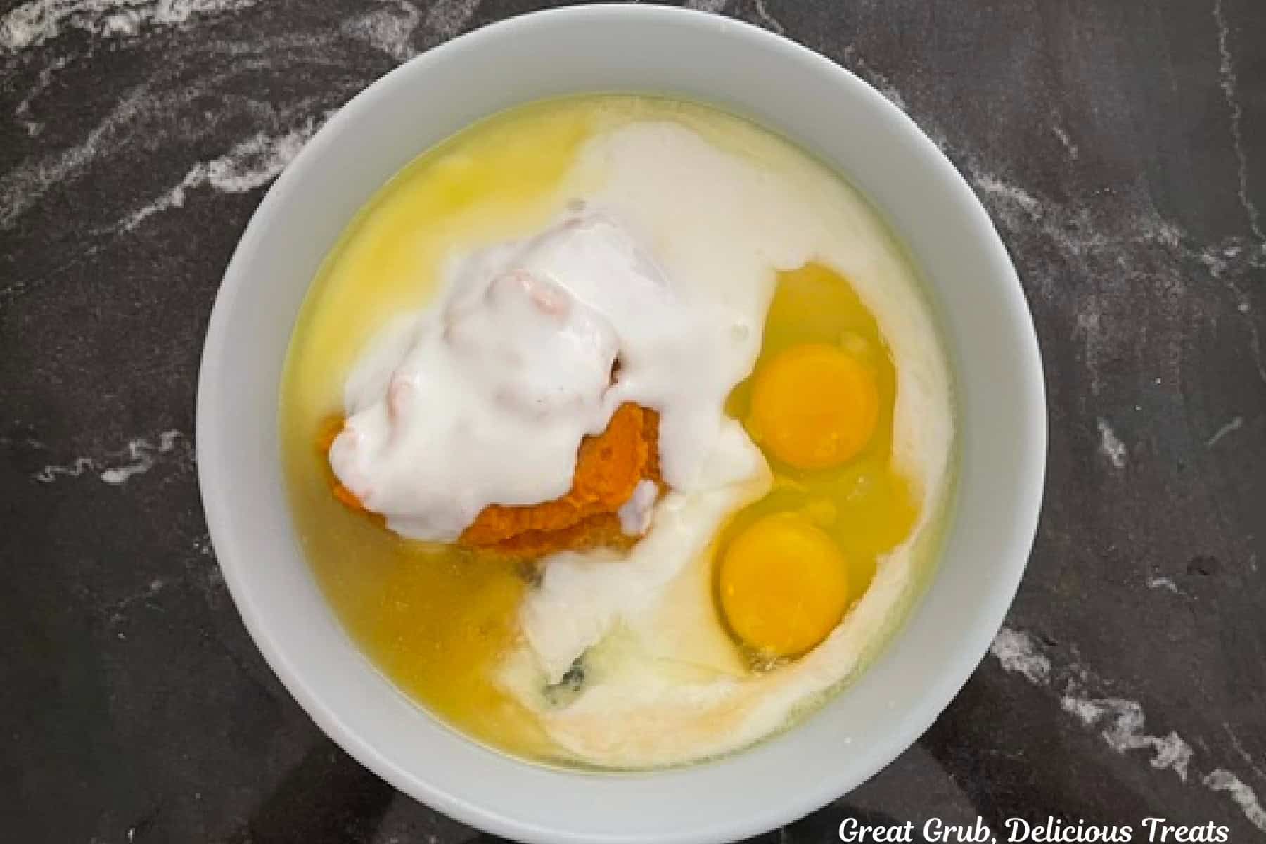 A large mixing bowl with the wet pumpkin spice waffle ingredients in it before being combined.