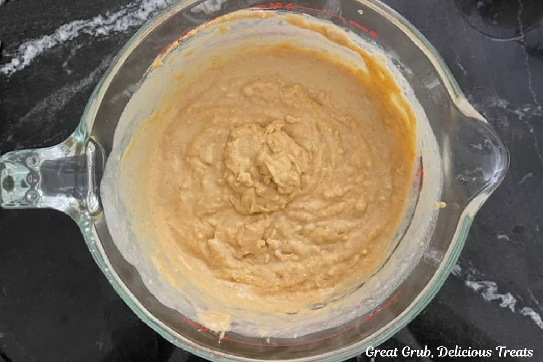 Pumpkin spice waffle batter in a large measuring cup with a pour spout.