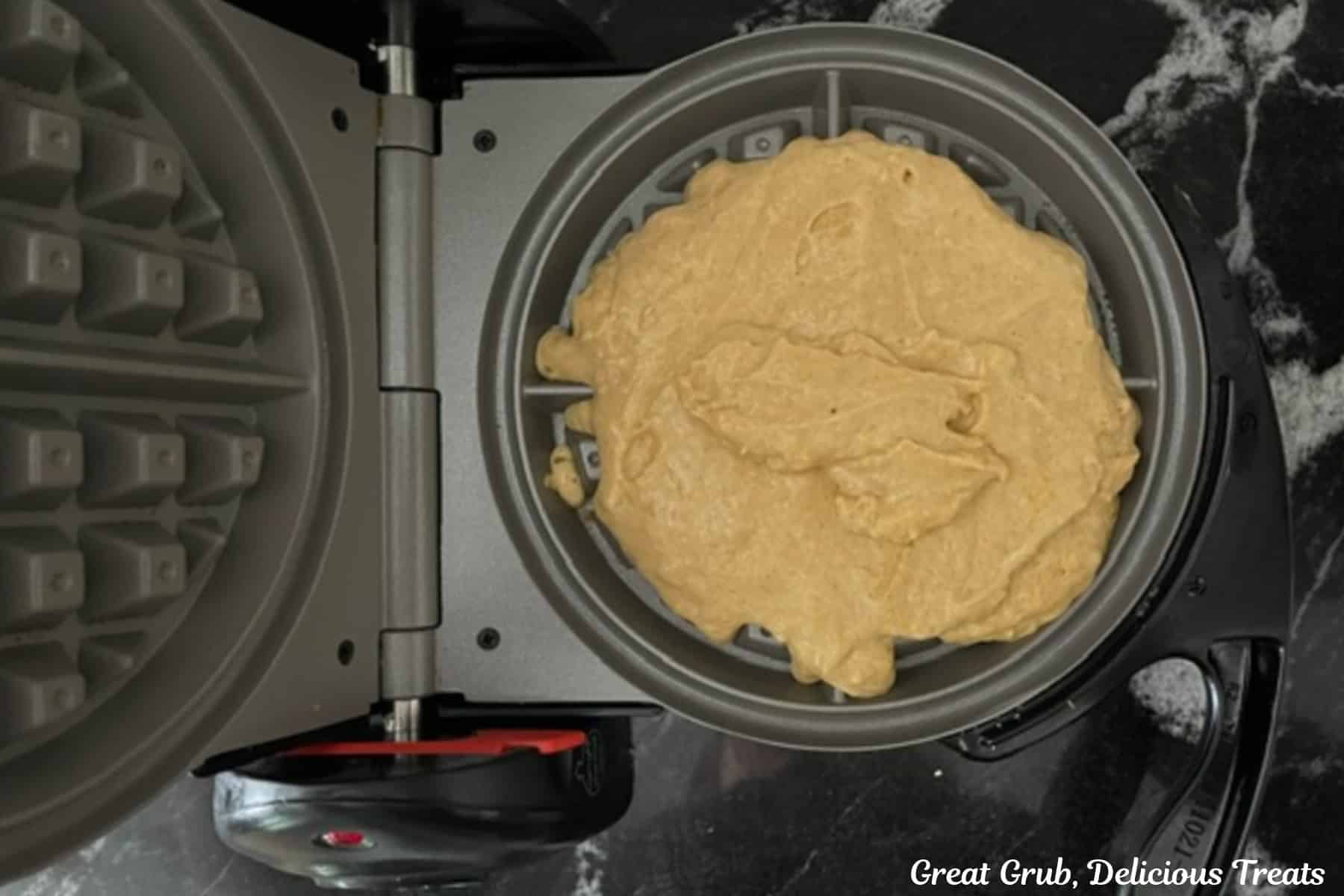 A waffle iron with waffle batter in it before being cooked.