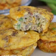 Four sausage egg bites on a plate with a bite taken out of the egg bite on top.