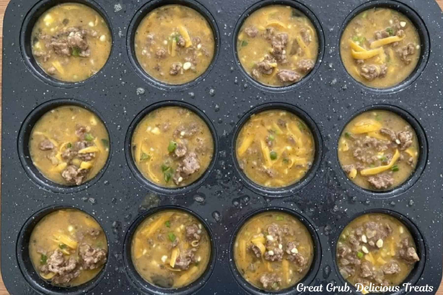 A 12-count muffin tin filled with sausage egg mixture before being baked.