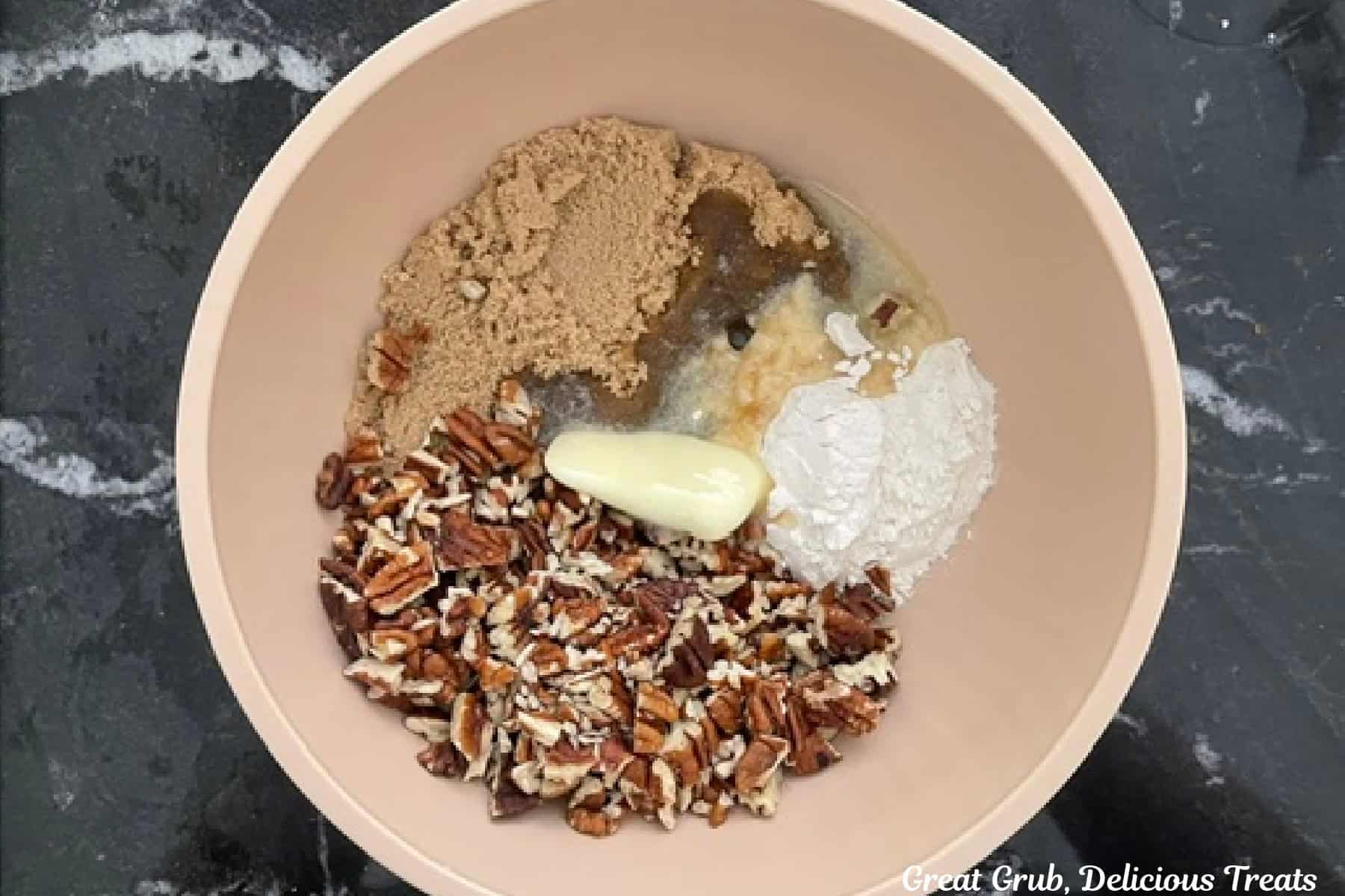A mixing bowl with chopped pecan, brown sugar, flour, and melted butter in it before being mixed together.