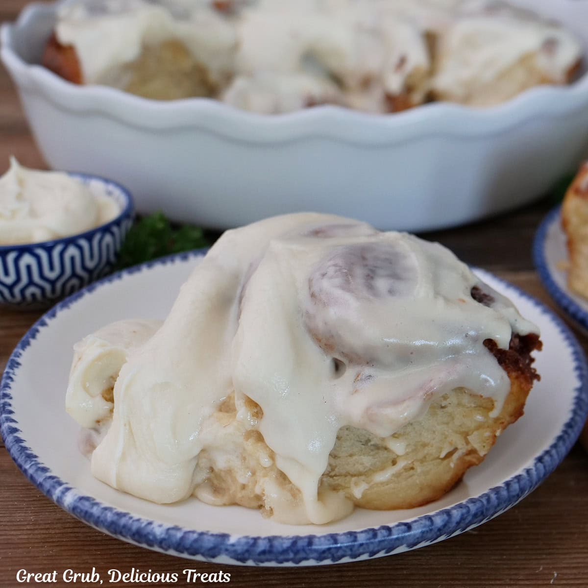 A banana cinnamon roll on a white plate topped with cream cheese icing.