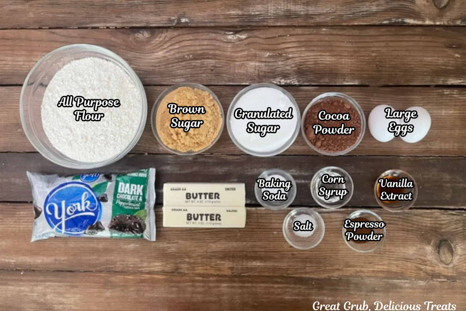 A rustic wood surface with all the ingredients placed on it to make dark chocolate York peppermint cookies.