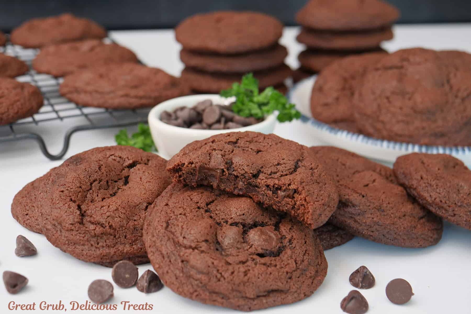 Dark chocolate cookies placed on a white surface with York peppermint chips placed around the cookie.