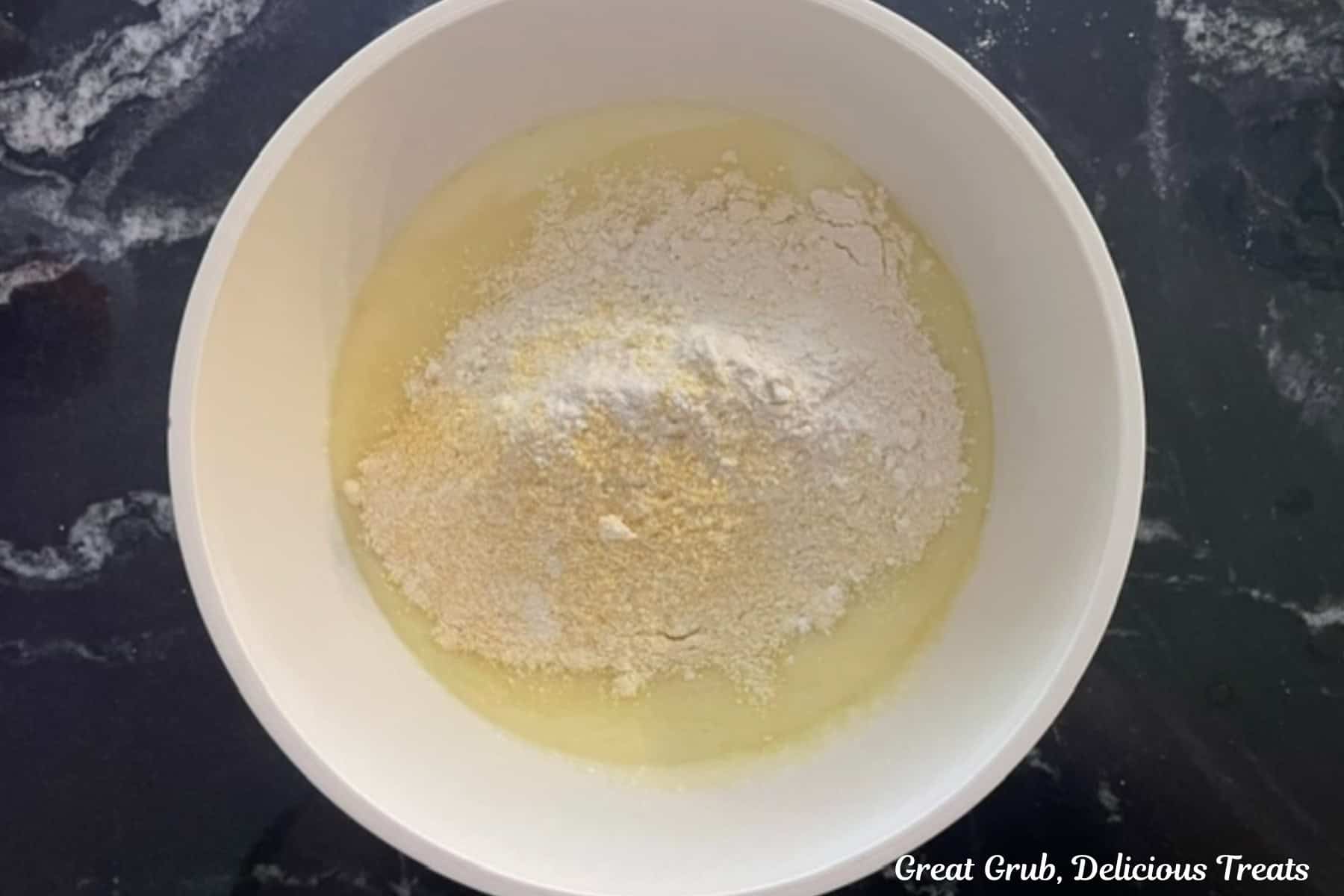 A white mixing bowl with the wet and dry cornbread ingredients in it.