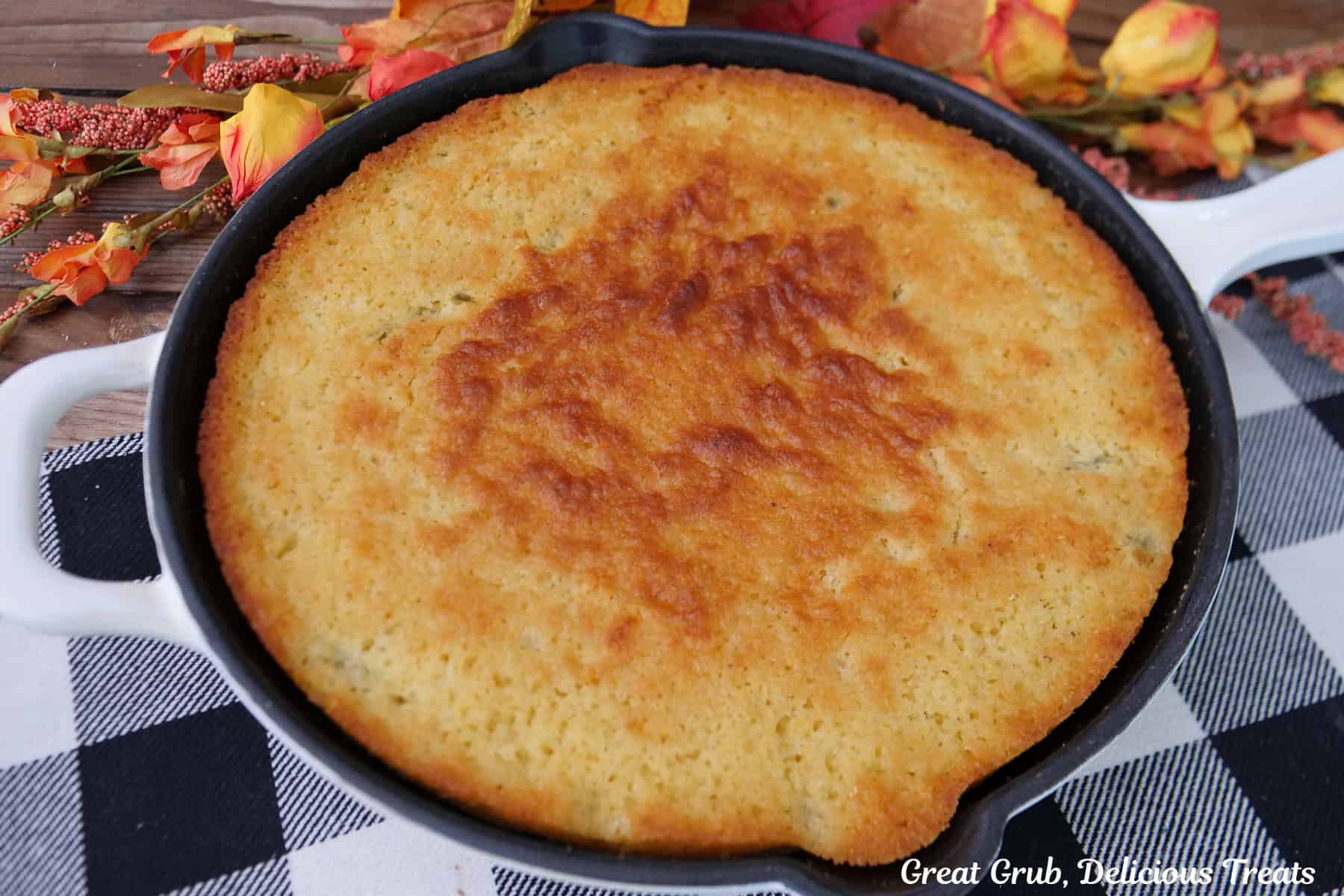 A black and white placemat with jalapeno cornbread in a round cast iron skillet.
