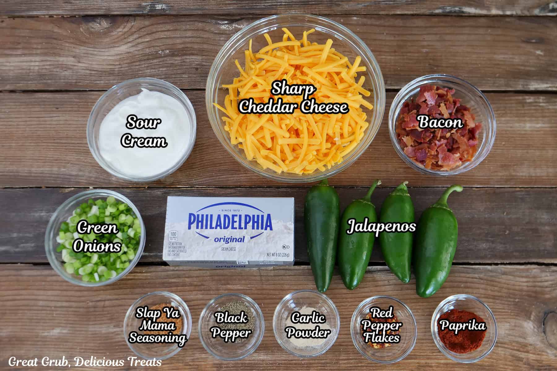 A rustic wood surface with all the ingredients placed on it to make jalapeno popper dip.