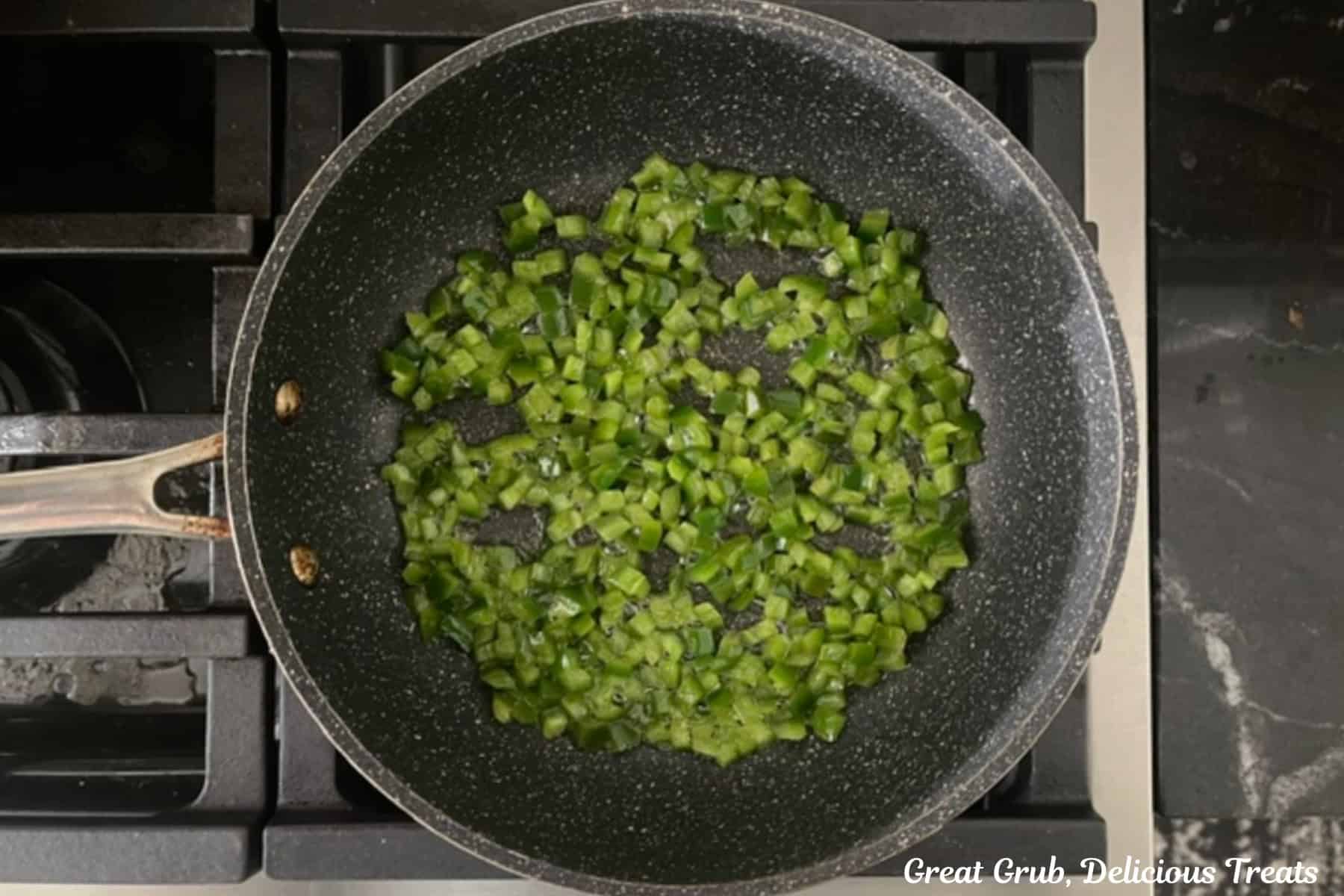 A frying pan with sauteed diced jalapenos in it.