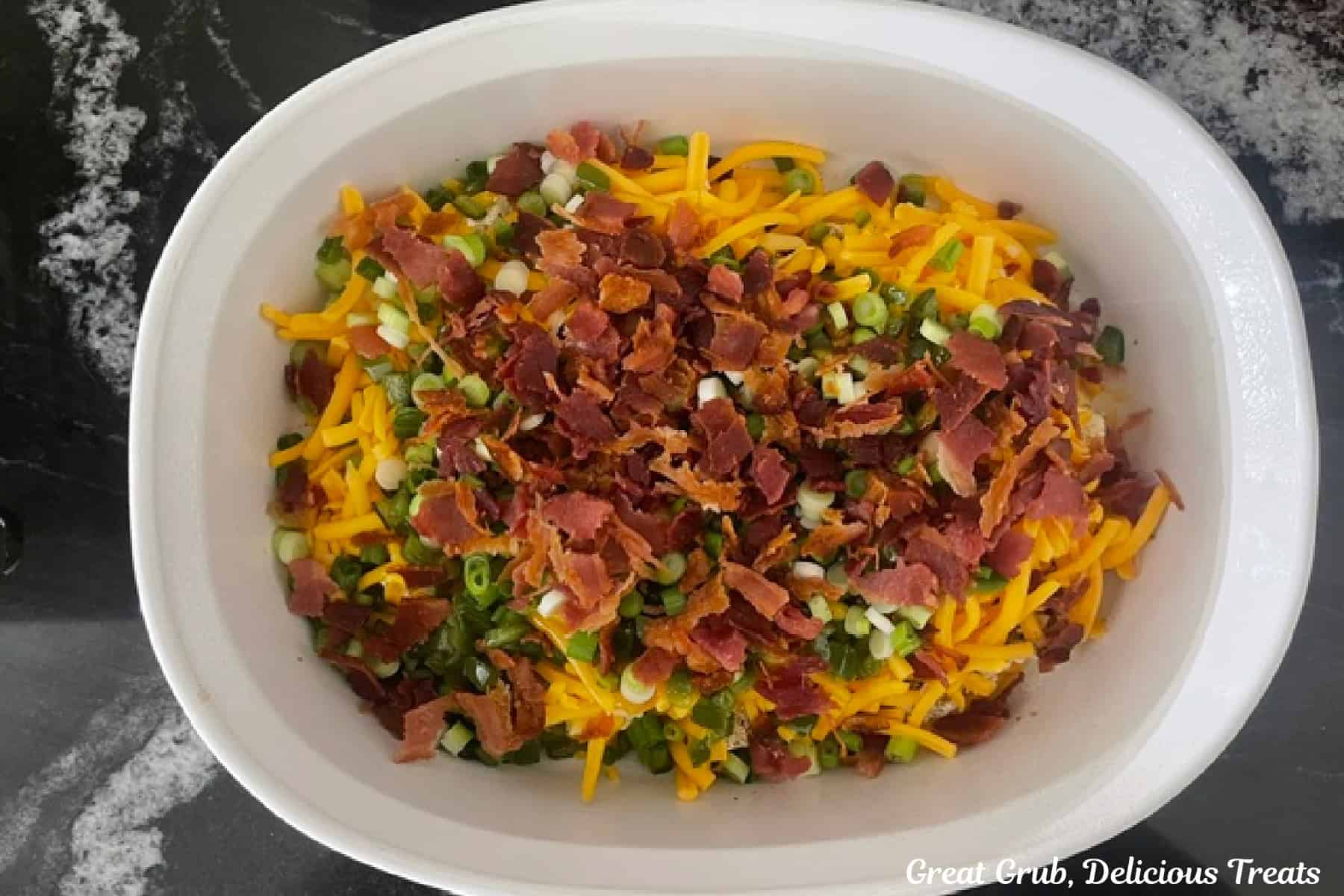 A white baking dish filled with jalapeno popper dip before it is baked in the oven.