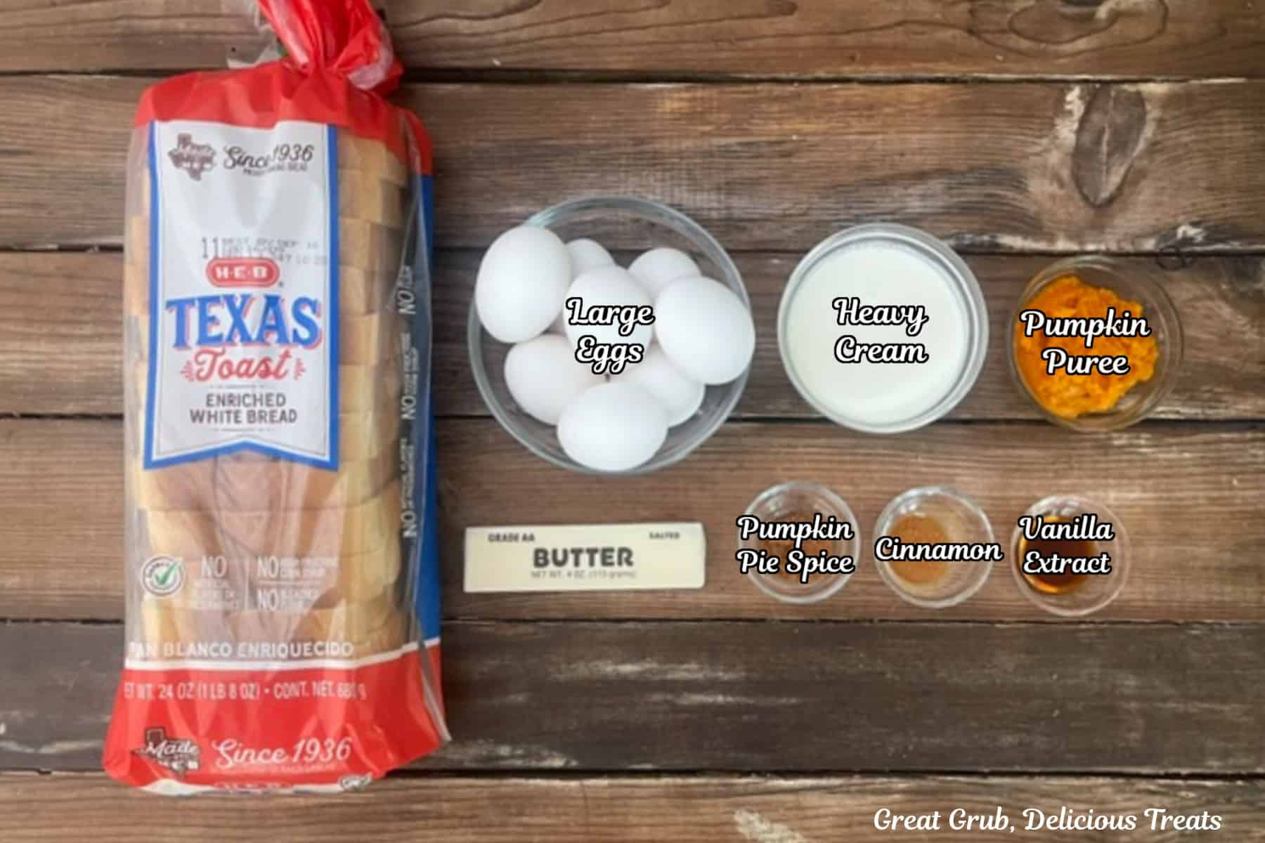 A rustic wood surface with all the ingredients placed on it to make pumpkin spice French toast.