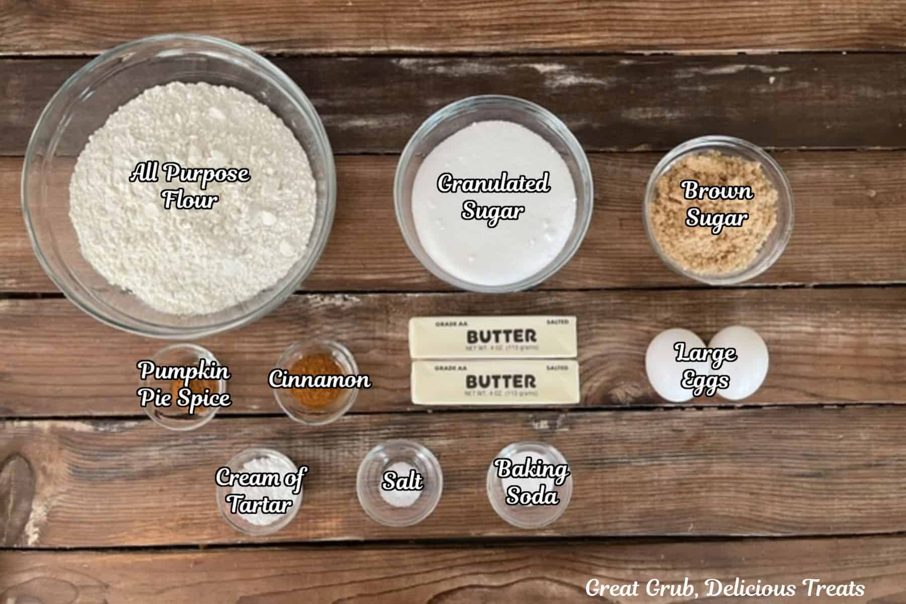 A rustic wood surface with all the ingredients placed on it to make pumpkin spice snickerdoodle cookies.
